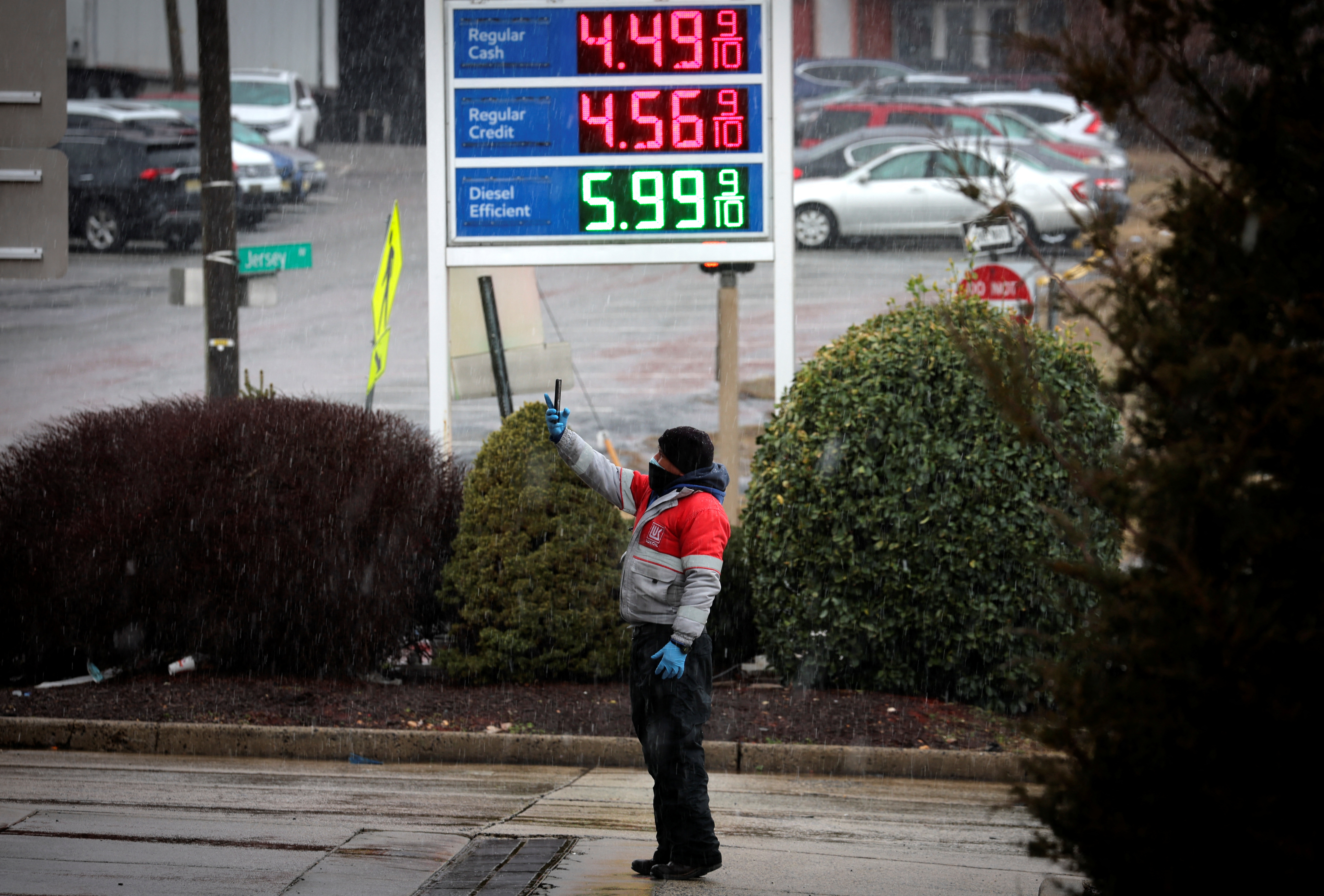 A worker takes pictures of gasoline prices at a gas station, following Russia's invasion of Ukraine, in Jersey City, New Jersey, March 9, 2022.