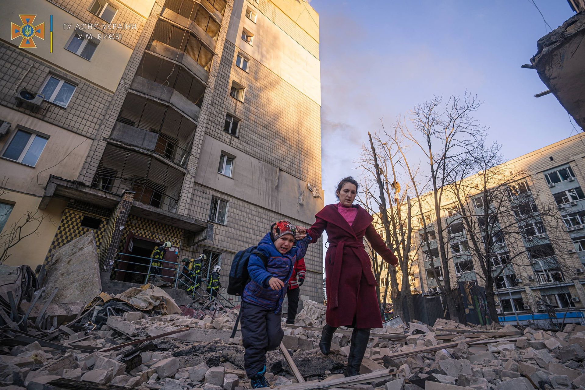 A woman with a child evacuates from a residential building damaged by shelling, as Russia's attack on Ukraine continues, in Kyiv, Ukraine, in this handout picture released March 16, 2022.