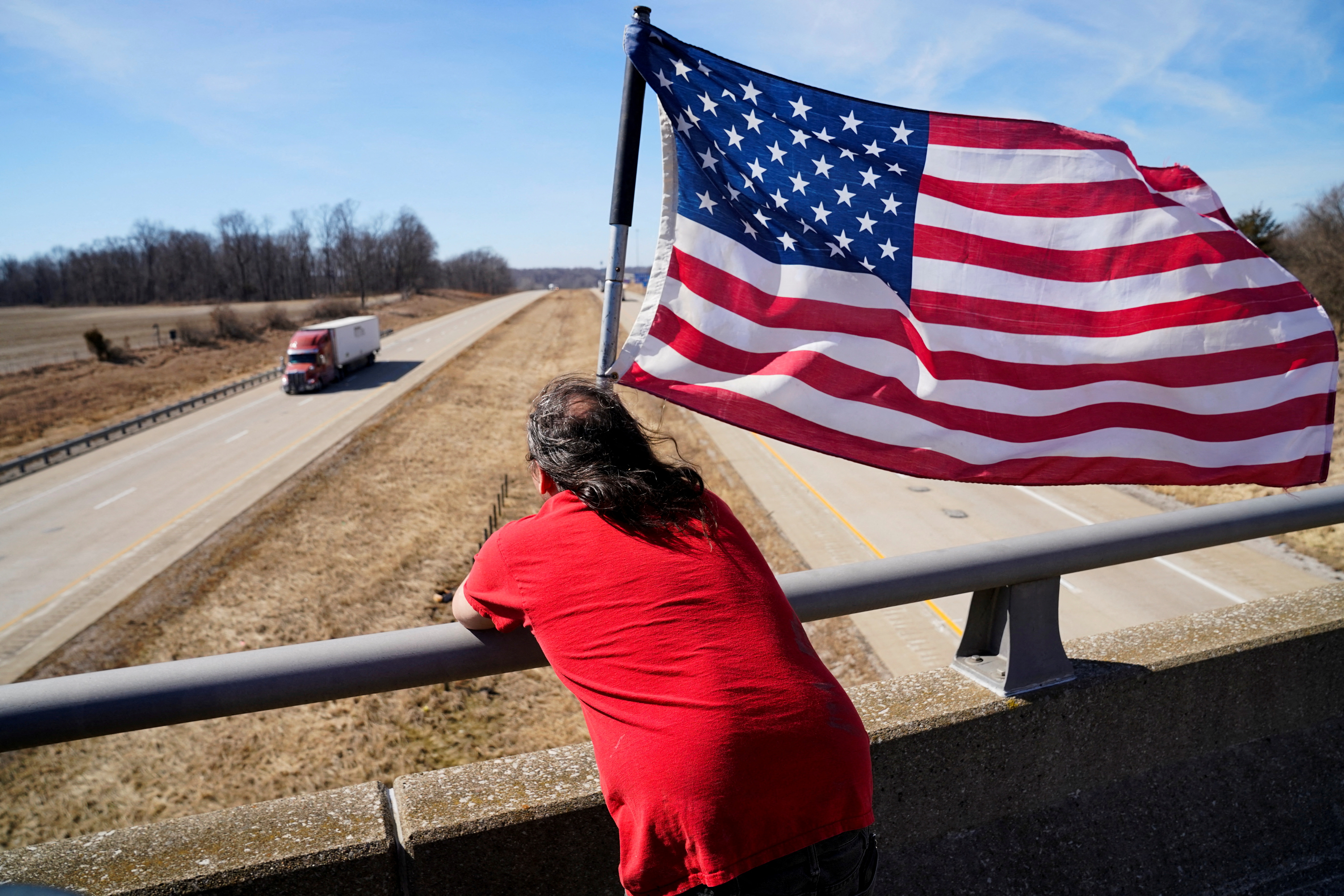 Dave Woods, 47, waits on an overpass in support for trucks driving in a convoy bound for the nation's capital to protest against coronavirus disease vaccine mandates, in Wabash Township, Illinois, March 1, 2022.