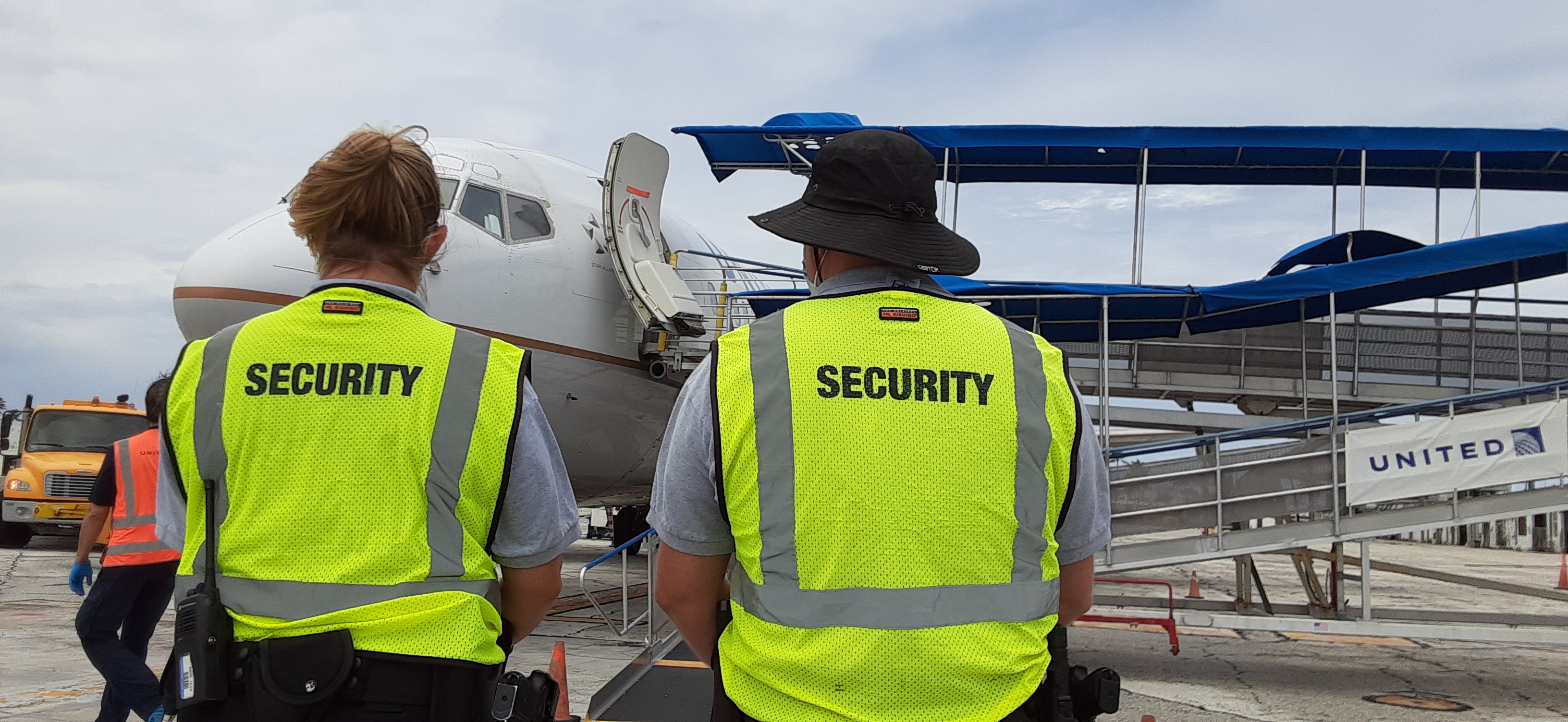 Two security officers at the U.S. Army base at Kwajalein Atoll stand by as a repatriation group arrives from Honolulu to begin a two-week quarantine at the Army base.