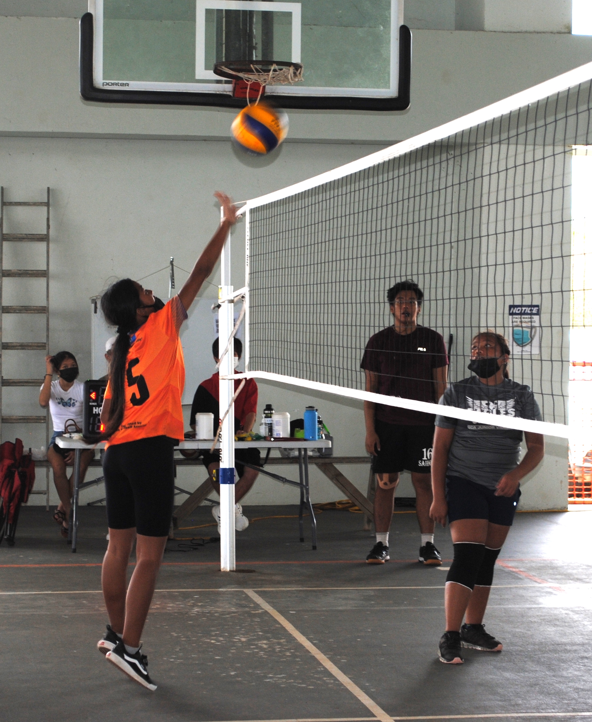 A Tanapag Middle School player tips the ball over the net.