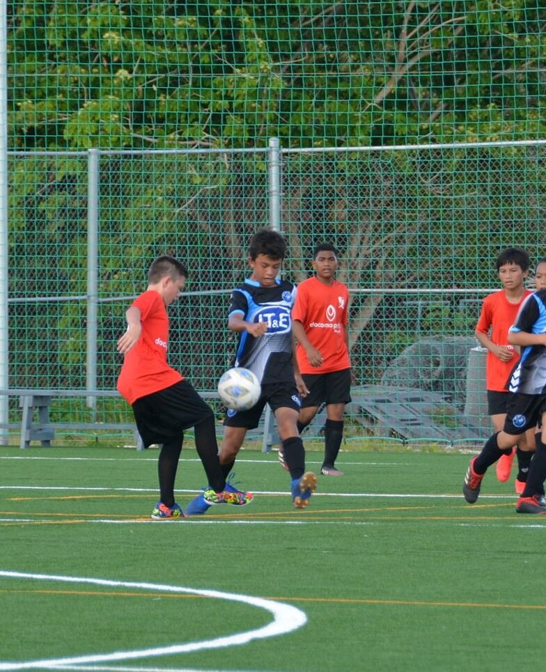 Paire 's Malachai Branno attempts the steal against MP United's Taiga Namai-Scoggins during a U13 boys division game of the TakeCare Youth Soccer League on Saturday at the NMI Soccer Training Center.