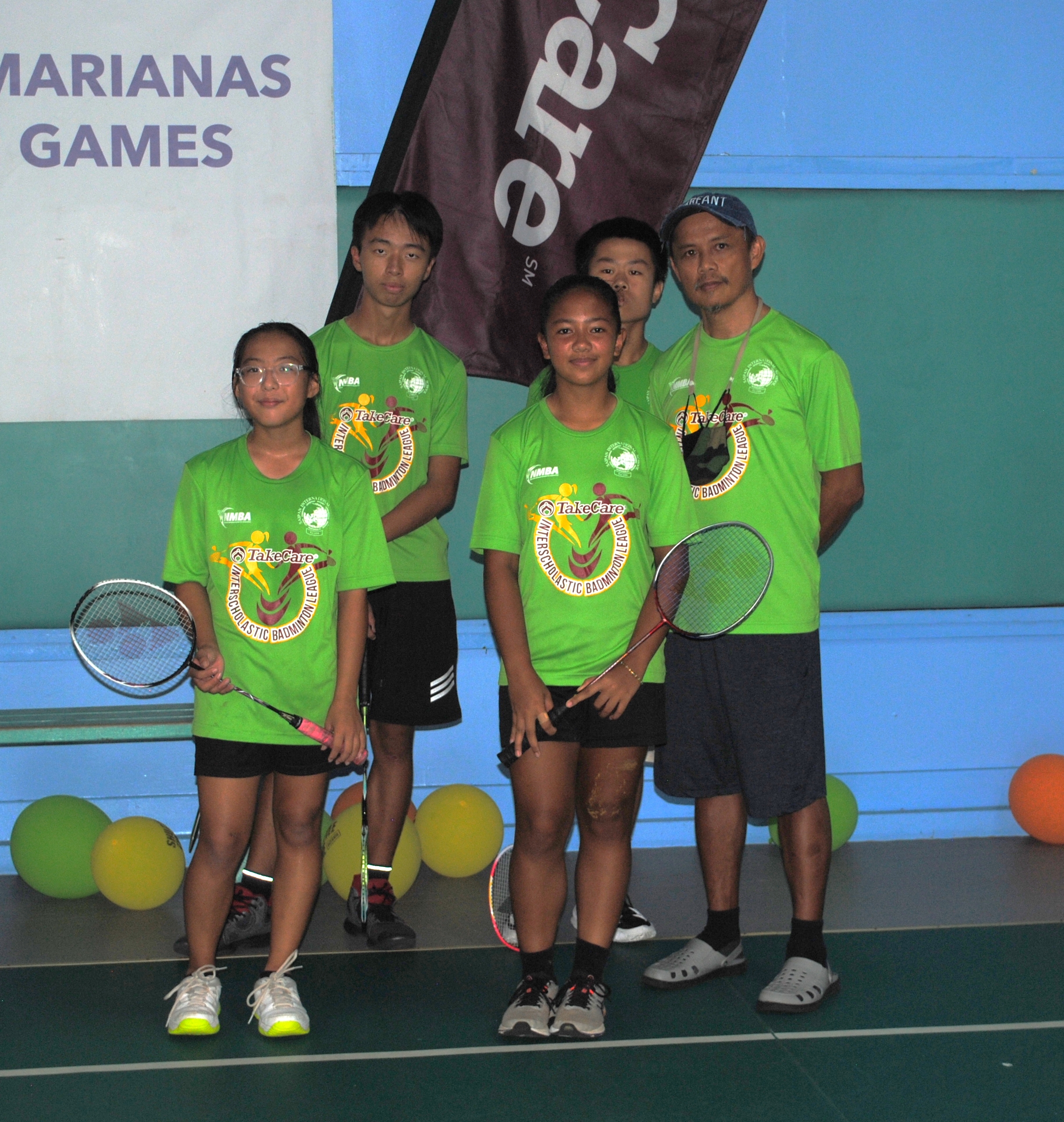 The SIS middle school team members pose for a photo with their coach Fred Guintu before the start of the TakeCare Interscholastic Badminton League championship at the TSL Sports Complex.