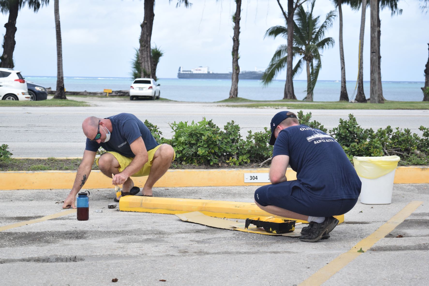 Crewmembers of the U.S. Coast Guard Cutter Oliver Henry paint the parking stops at the CDA building on Beach Road in San Jose Saturday.