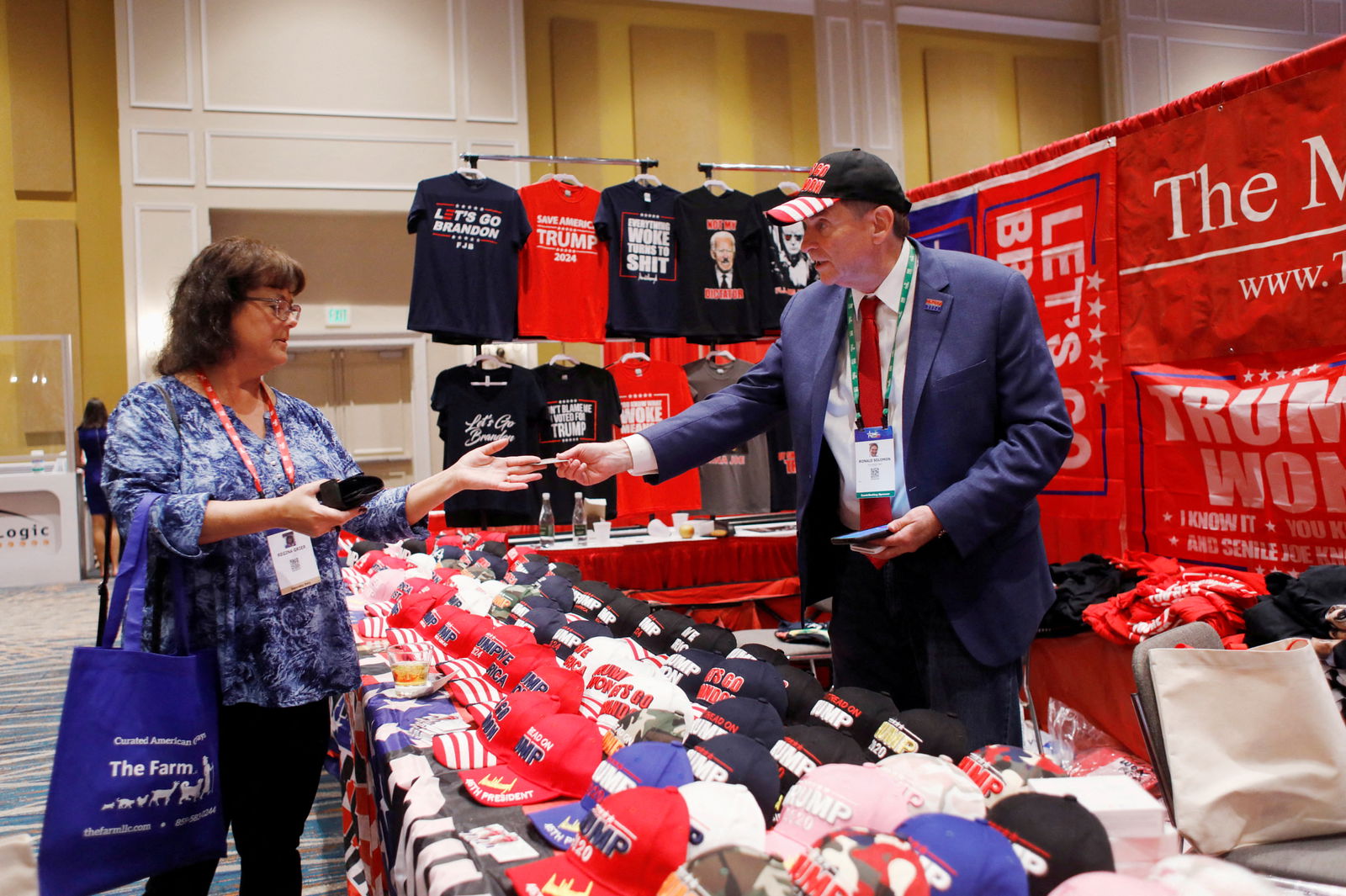 MAGA Mall President Ronald Solomon sells merchandise to Regina Grier at his vendor booth at the Conservative Political Action Conference in Orlando, Florida, Feb. 26, 2022.