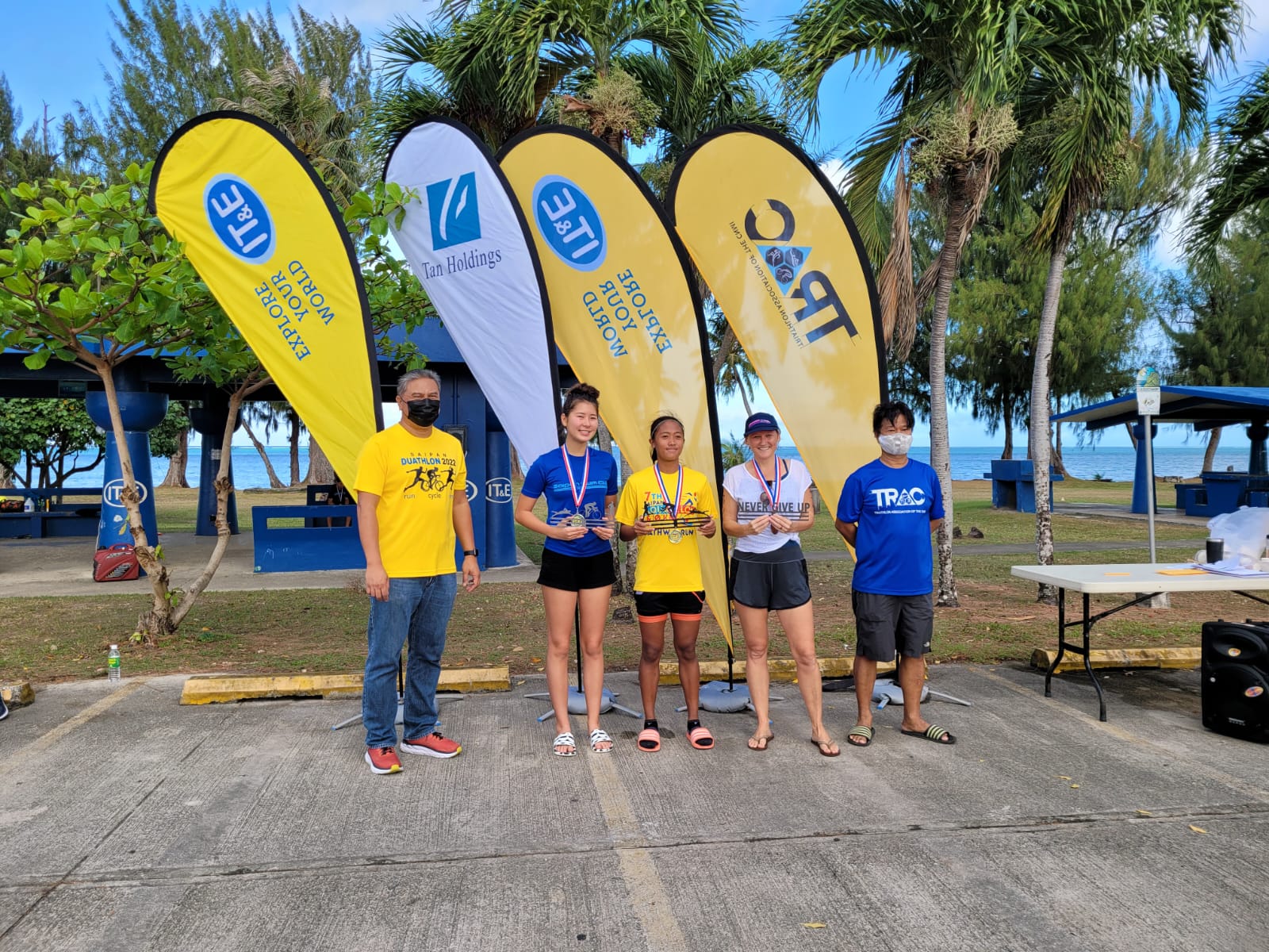 With their trophies and medals, 7th Aquathon women winners Jinnie Thompson, Kaithlyn Chavez and Nash Lindsay pose for a photo with Triathlon Association of the CNMI officials