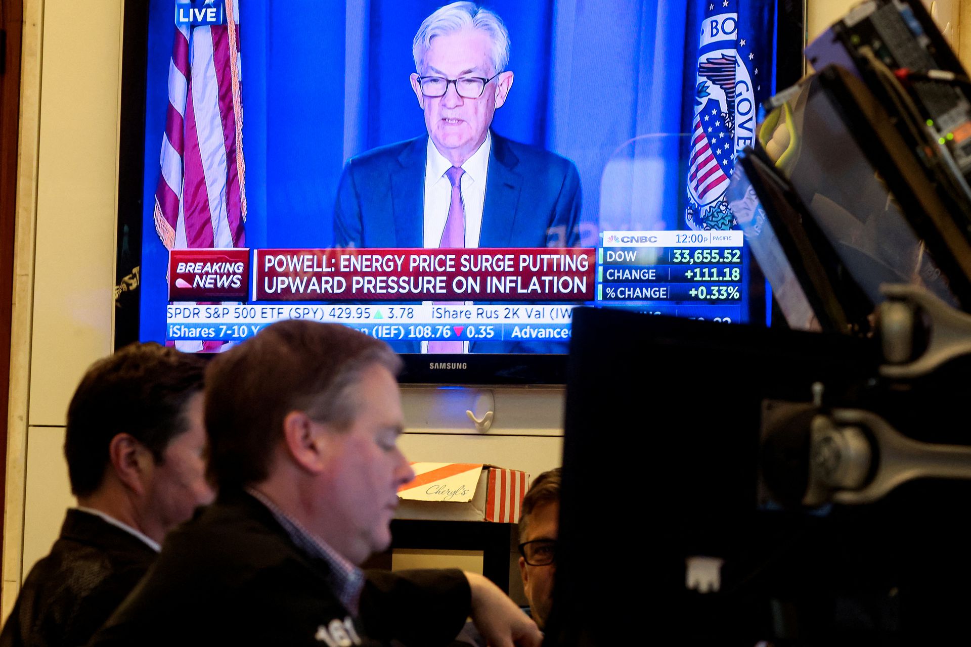 Traders work as Federal Reserve Chair Jerome Powell is seen delivering remarks on a screen at the New York Stock Exchange in New York City, March 16, 2022.