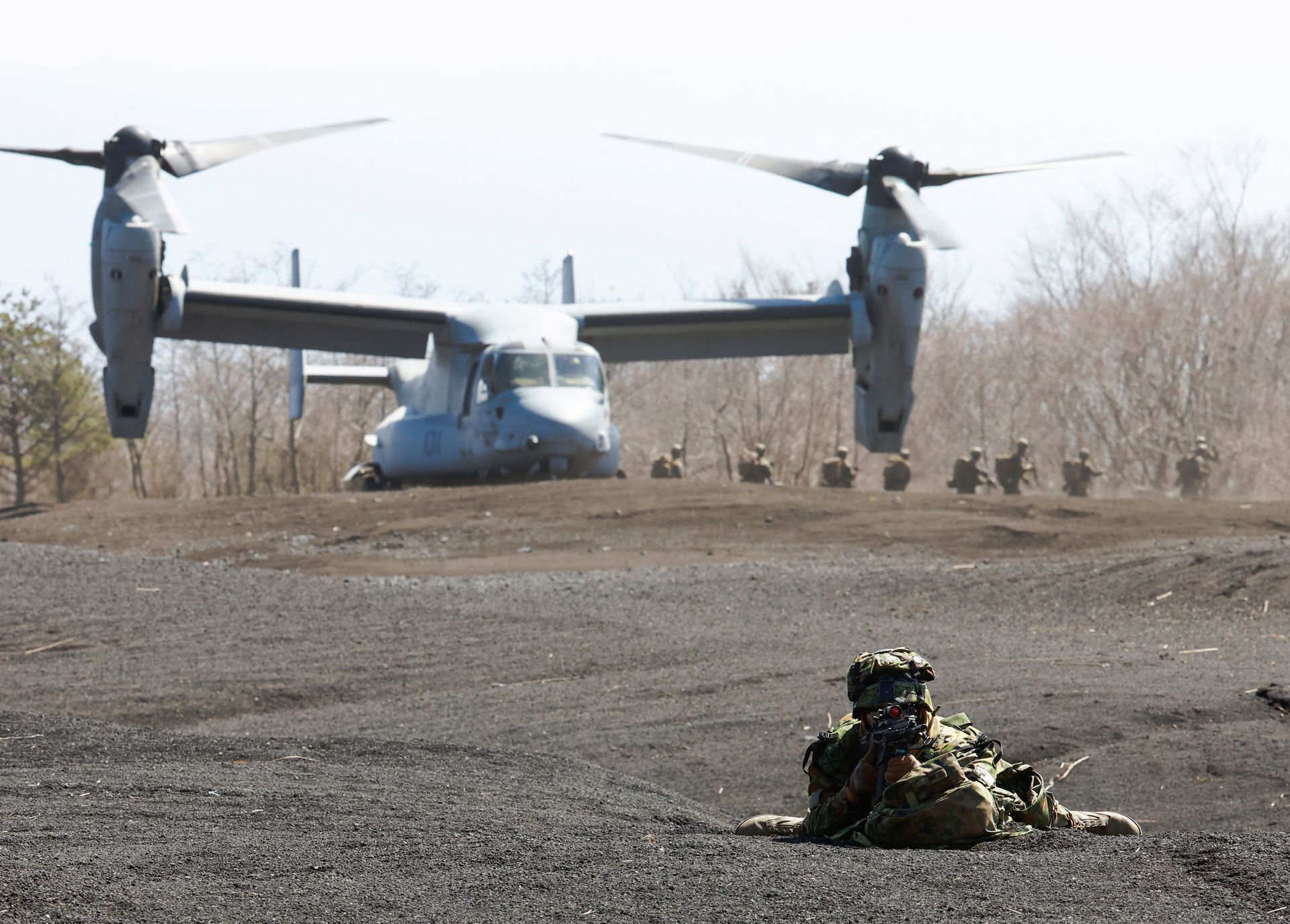 A member of the Japanese Self-Defense Force’s Amphibious Rapid Deployment Brigade takes a position while U.S. Marine Corps members get out of its MV-22 Osprey during a joint airborne landing exercise with the U.S. Marine Corps in Gotemba, west of Tokyo, Japan on March 15, 2022.