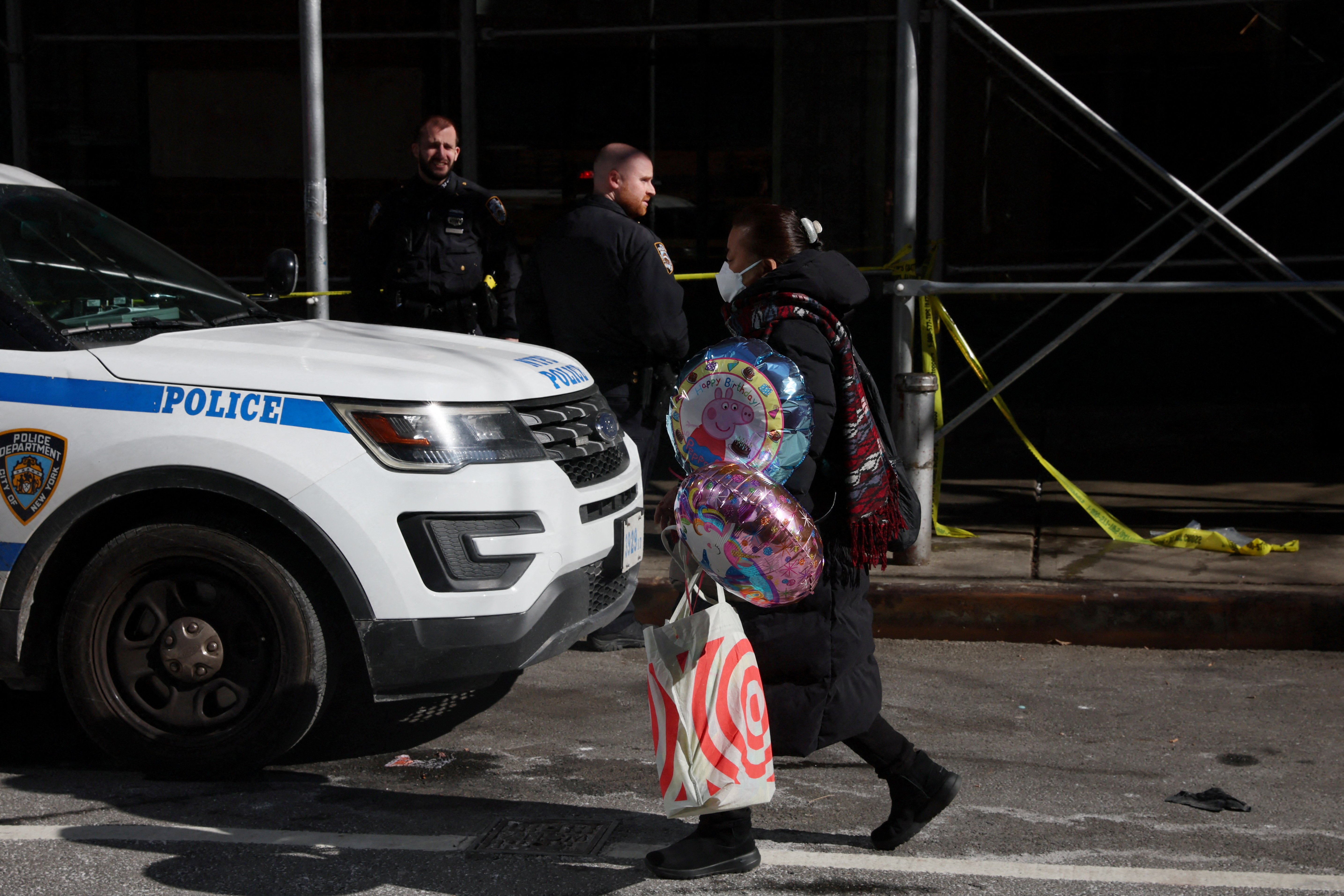 A woman walks with balloons by an area where NYPD police have marked off an area where a 43-year-old man was found dead on Sunday evening in New York City, March 14, 2022.