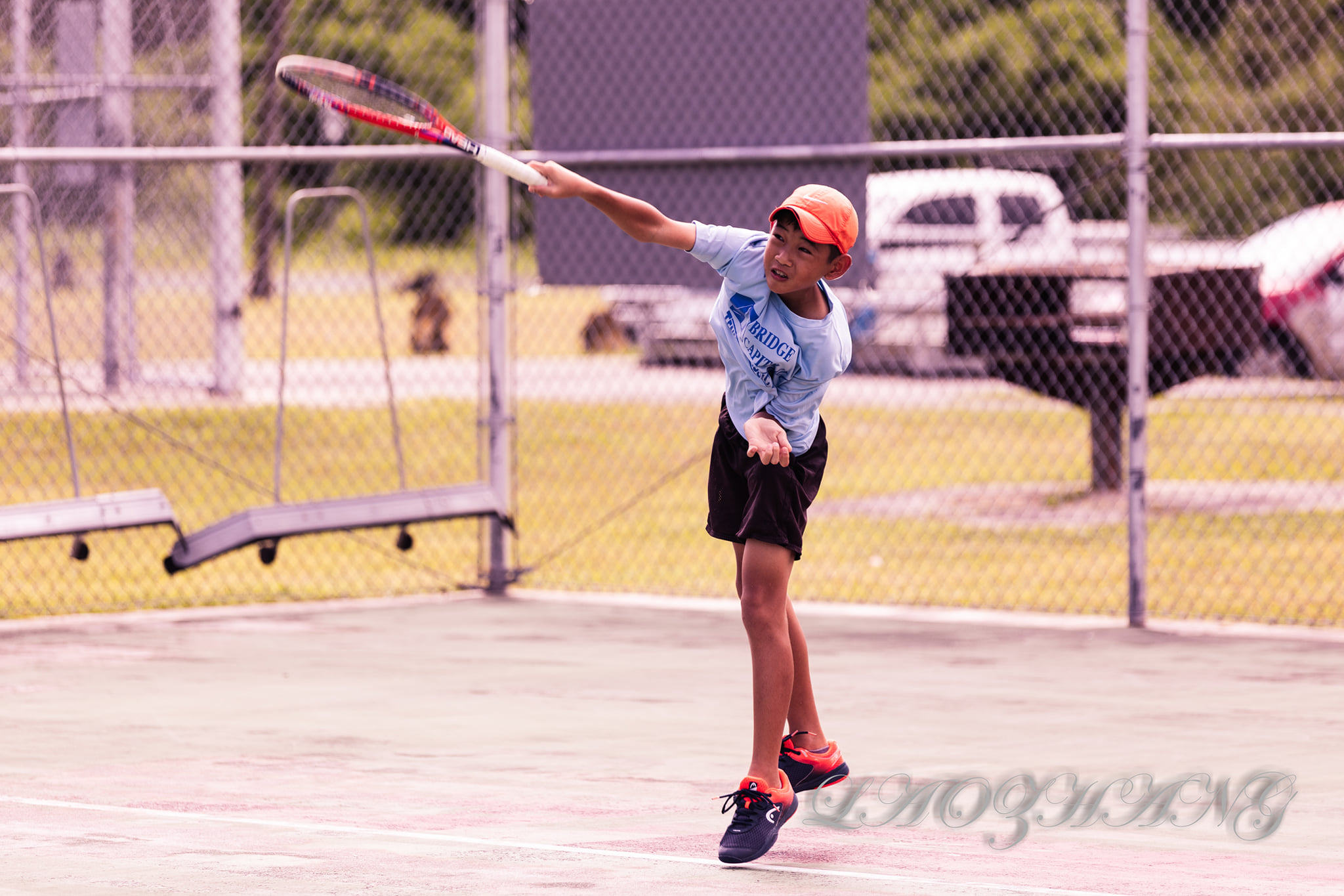 Yutaka Kadokura connects the overhead serve during a Bridge Capital Tennis Classic match at an American Memorial Park tennis court over the weekend.