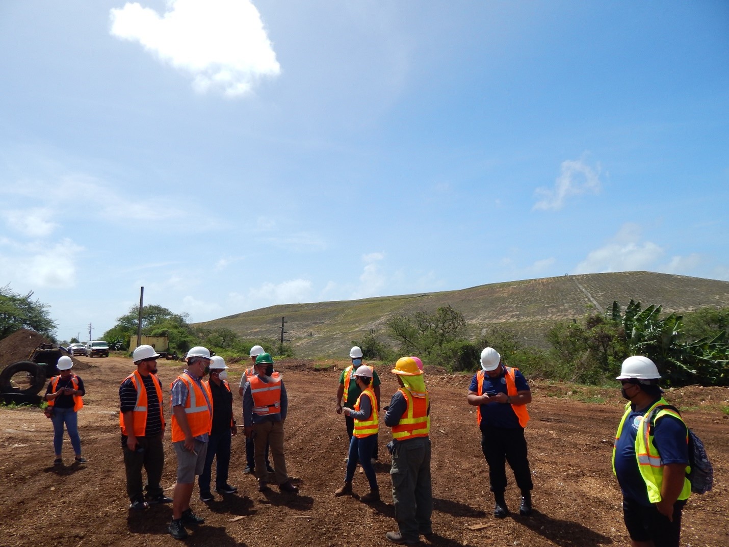 Representatives from the Guam Environmental Protection Agency, CNMI Office of Planning and Development Solid Waste team, Department of Public Works Tinian, and the Bureau of Environmental and Coastal Quality learn more about the work being done at the Ordot Green Waste Facility in Guam. In the background is the former Ordot Landfill.