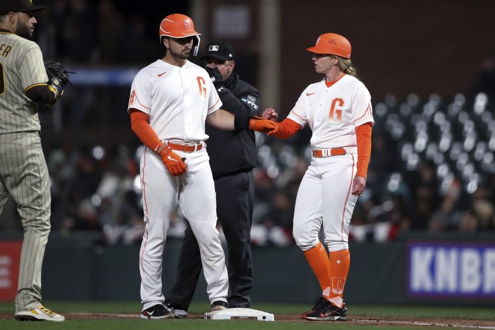 San Francisco Giants first base coach Alyssa Nakken fist-bumps Joey Bart after Bart singled against the San Diego Padres during the fifth inning of a baseball game in San Francisco on Tuesday.