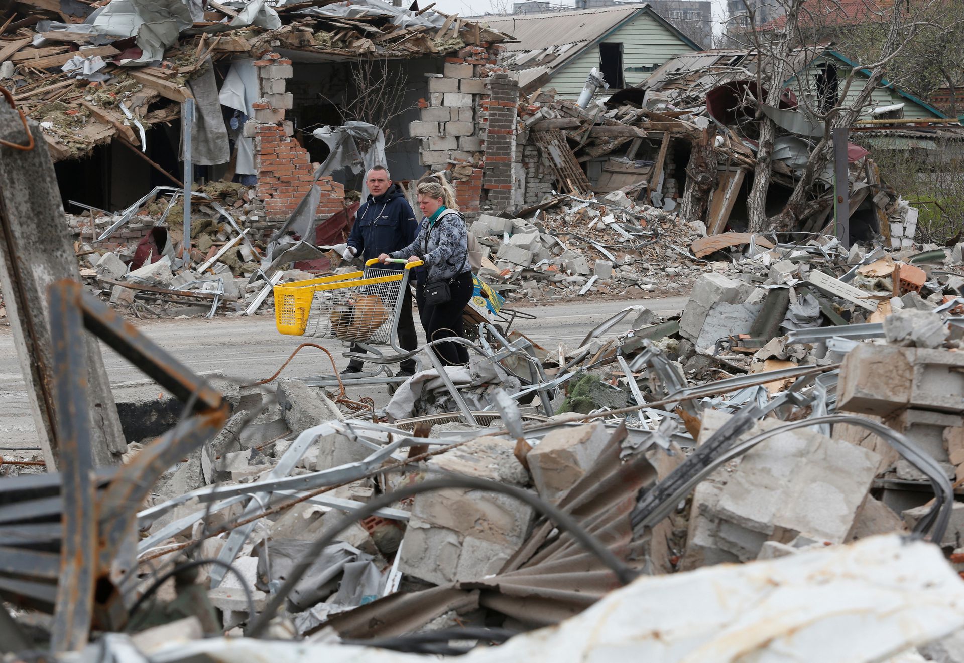 Local residents in the southern port city of Mariupol, Ukraine on April 19, 2022 walk past buildings destroyed during the Russian invasion of their country.
