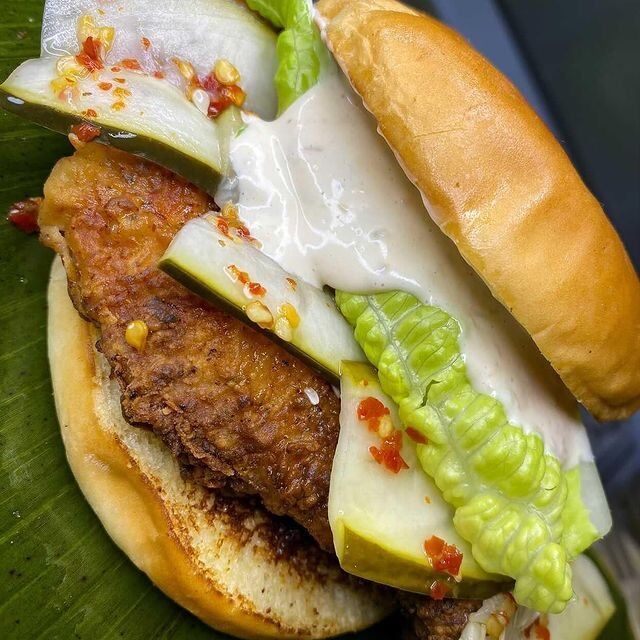 Adobo marinated fried chicken, sili pipino, roasted jalapeno sauce, and lettuce on a brioche bun