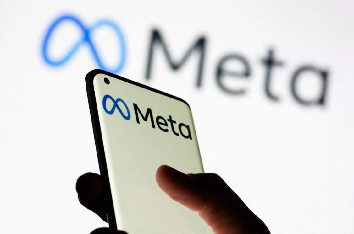 A woman holds a smartphone with the Meta logo in front of a displayed Facebook's new rebrand logo  in this illustration picture taken on Oct. 28, 2021.