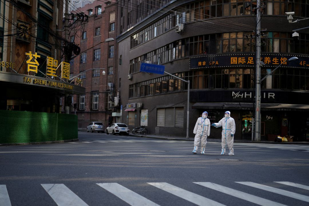 Workers in protective suits keep watch on a street during a lockdown, amid the coronavirus disease pandemic, in Shanghai, China, April 16, 2022.
