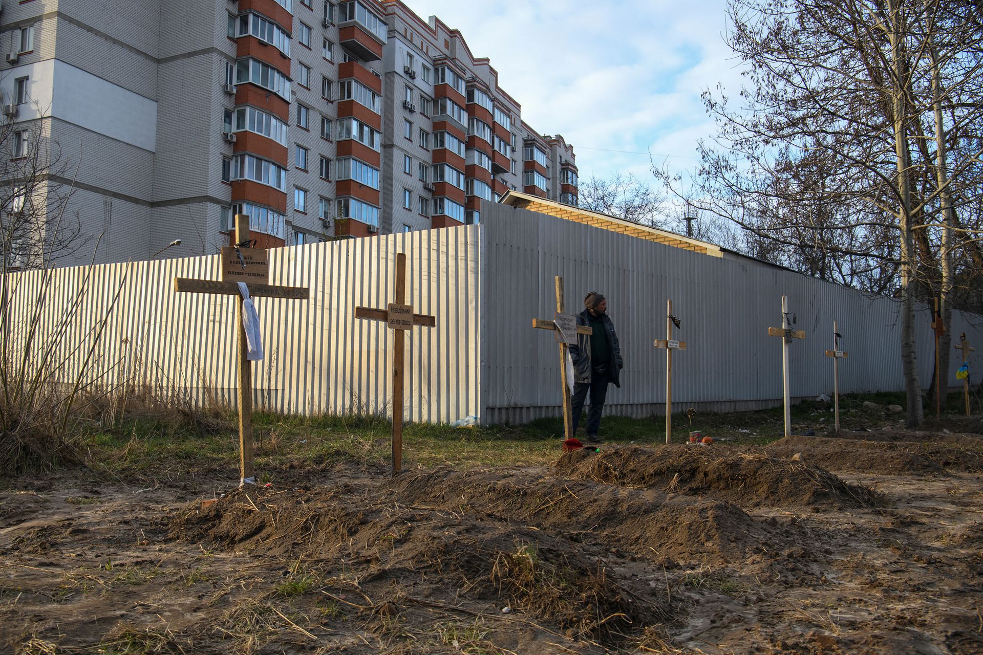 A man stands next to graves with bodies of civilians, who according to local residents were killed by Russian soldiers, as Russia's attack on Ukraine continues, in Bucha, in Kyiv region, Ukraine on April 4, 2022.