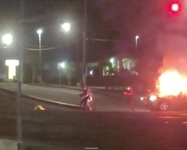 A screen capture from a reader-contributed video shows Guam police officers rushing toward a man slumped on the ground after he was shot at the intersection of Routes 16 and 27 early Friday morning. The man’s burning SUV is seen on the right.