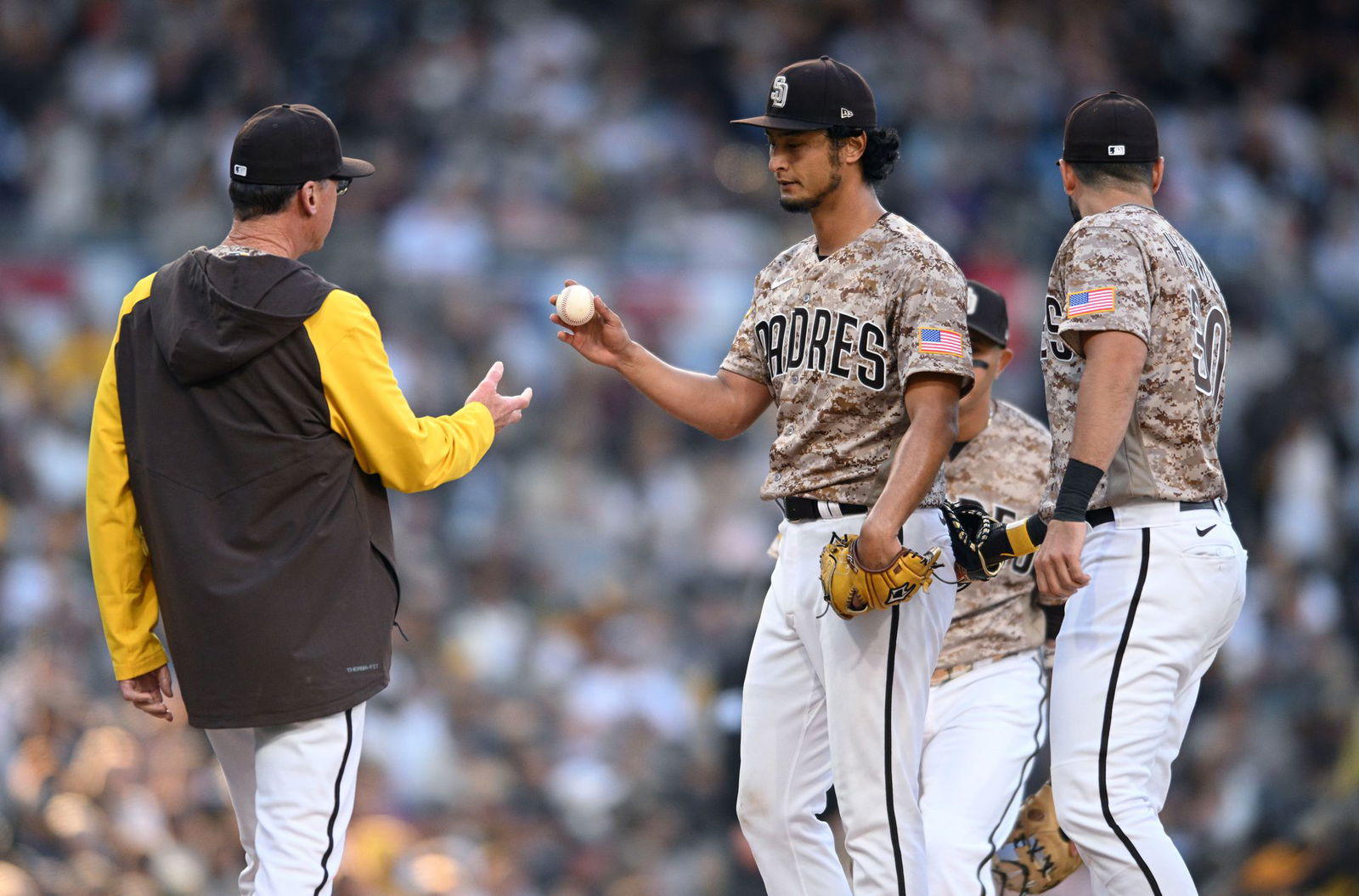 San Diego Padres starting pitcher Yu Darvish, center, hands the ball to manager Bob Melvin, left, during a pitching change in the seventh inning against the Atlanta Braves at Petco Park in San Diego, California, April 17, 2022.