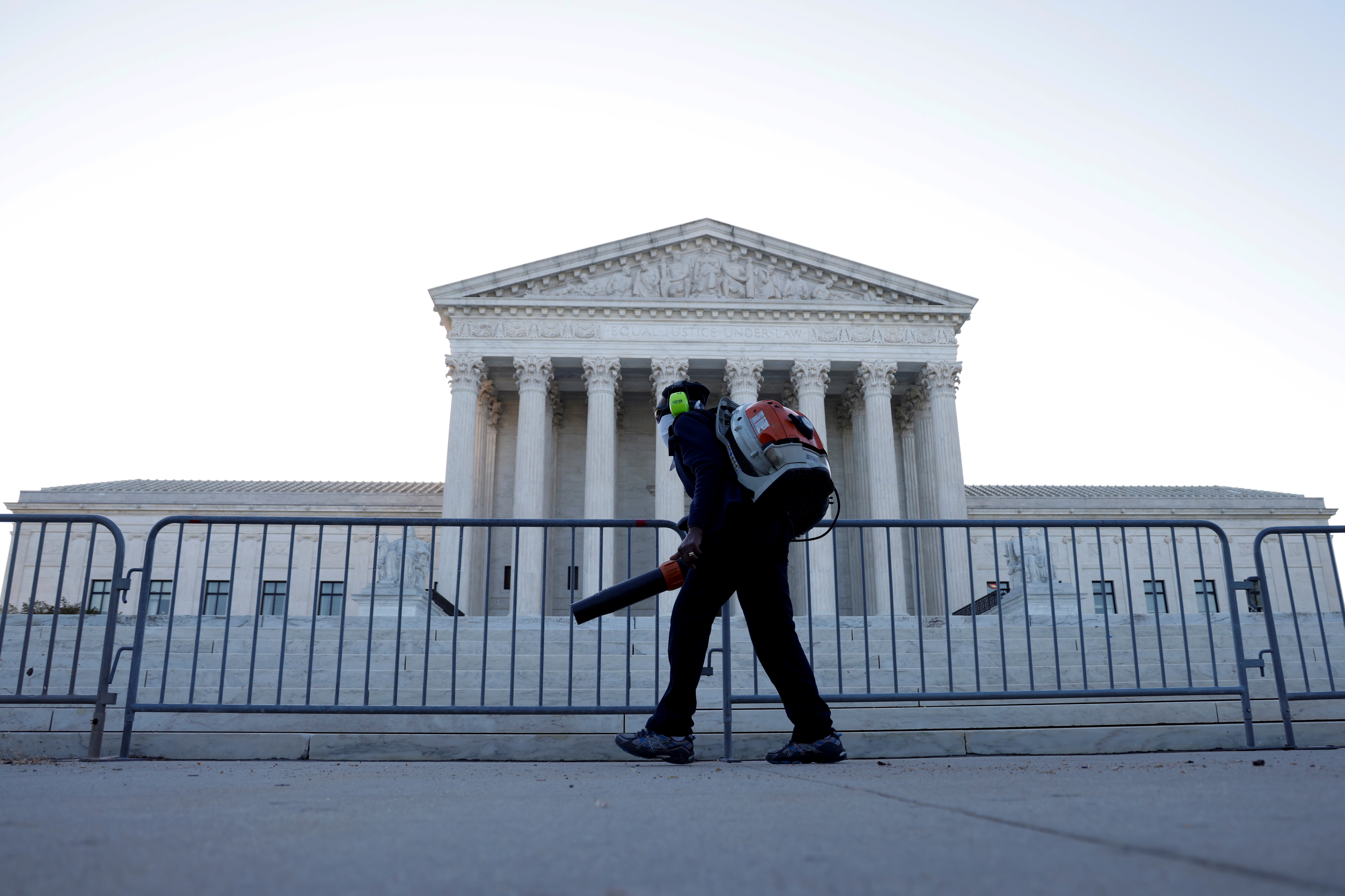 A worker clears front steps as morning rises over the U.S. Supreme Court building, still closed to the public due to Covid-19 pandemic, in Washington, D.C. April 26, 2021.