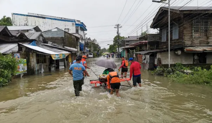 Coast guard and police personnel evacuate a resident from a flooded area in Abuyog town, Leyte province, southern Philippines.