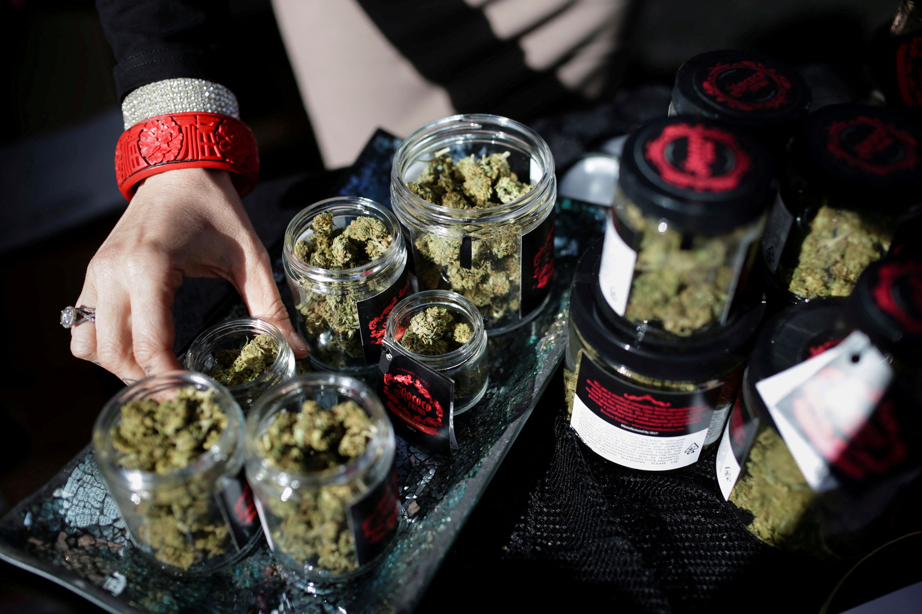 An employee puts down an eighth of marijuana after letting a customer smell it outside the Magnolia cannabis lounge in Oakland, California, April 20, 2018.