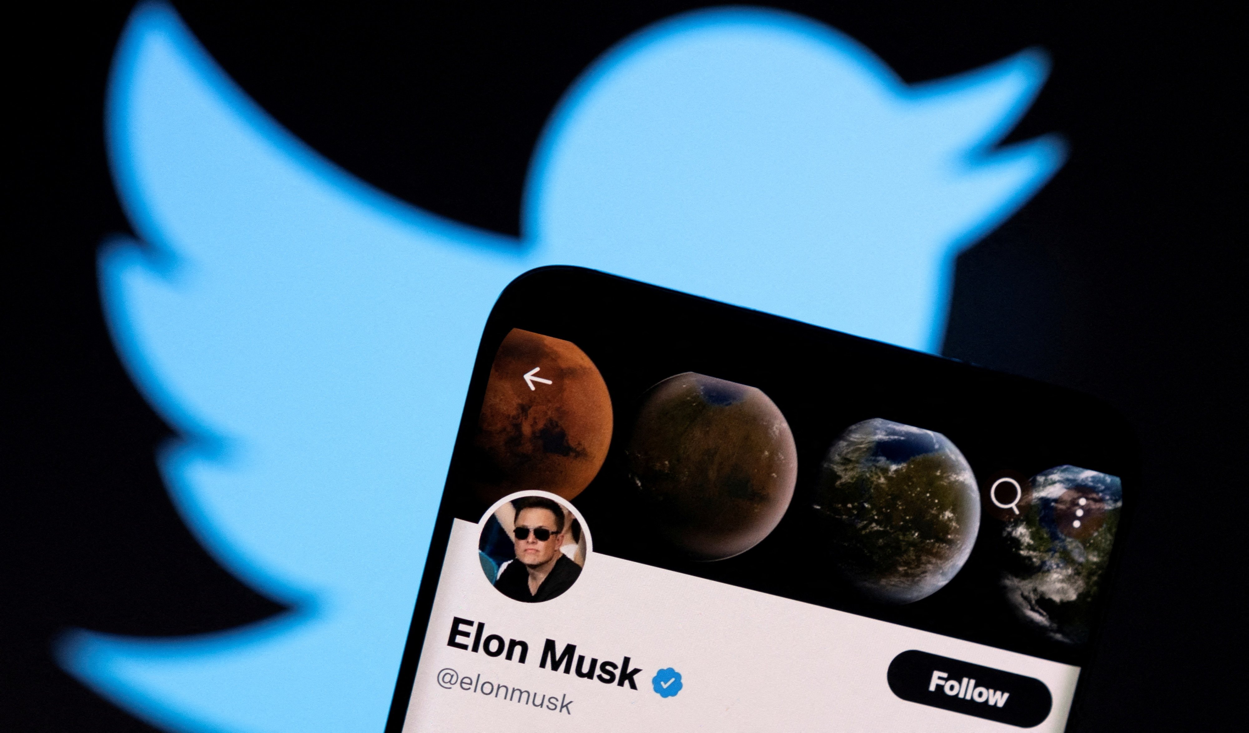 Elon Musk's twitter account is seen on a smartphone in front of the Twitter logo in this photo illustration taken April 15, 2022.