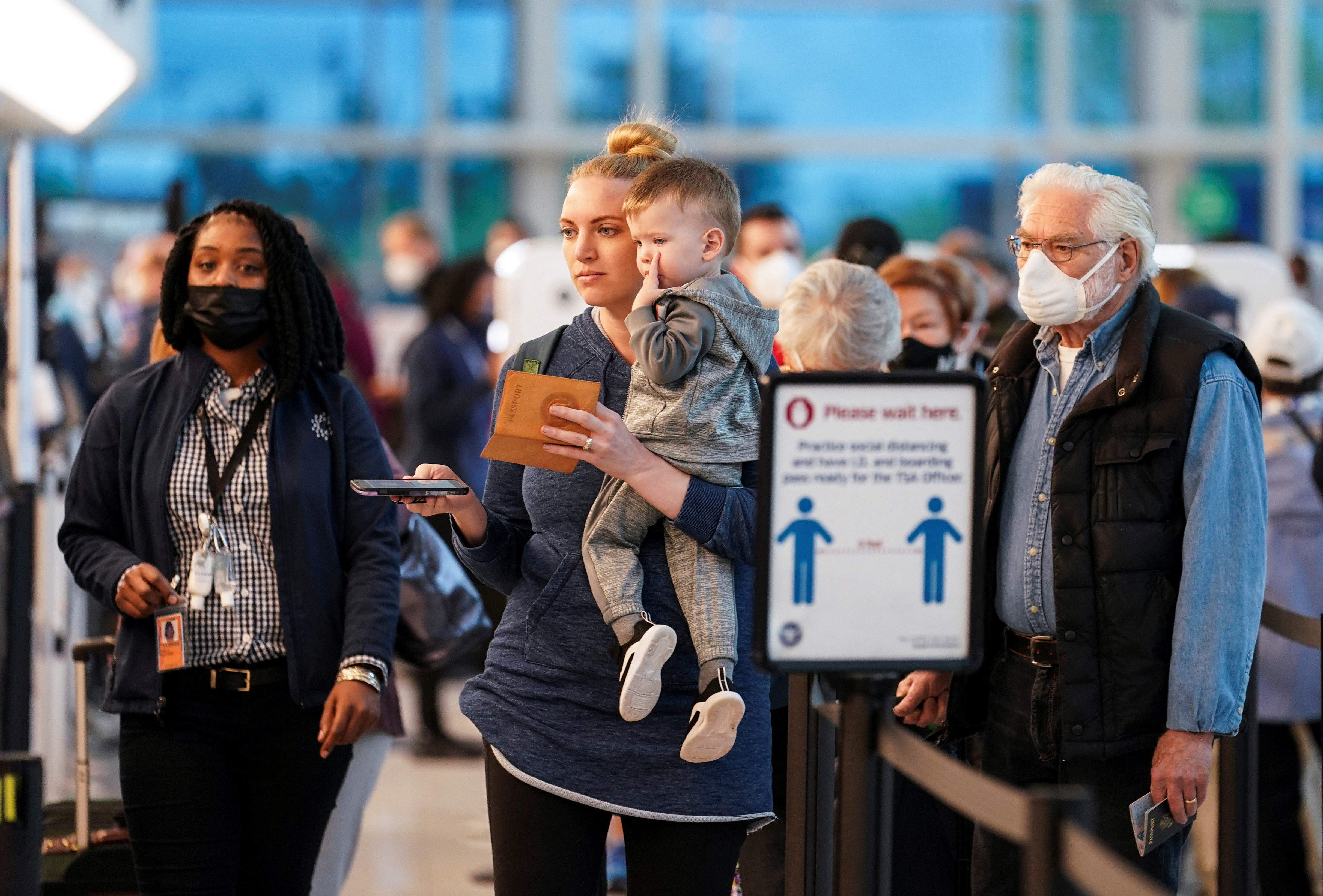 Masked and unmasked travelers line up in the security area at Ronald Reagan Washington National Airport in Arlington, Virginia, April 19, 2022.