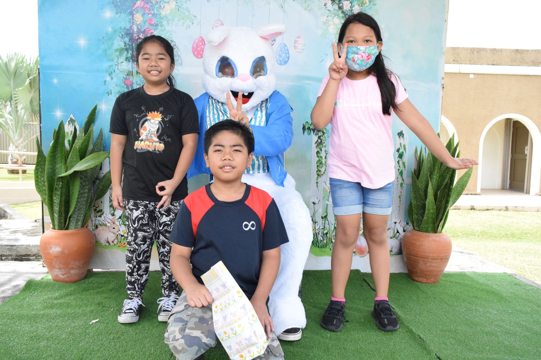 Johana Elizabeth Sarabia, right, and her best friend Emmjie Escano, left, and Escano's brother Benjie, center, pose with the Saipan Rotary Club Easter mascot.