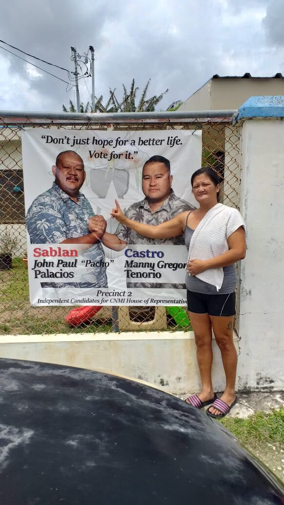 A property owner in Precinct 2 poses with the campaign sign that was re-installed by Rowina Ogo after the family allowed her to remove it on Good Friday.