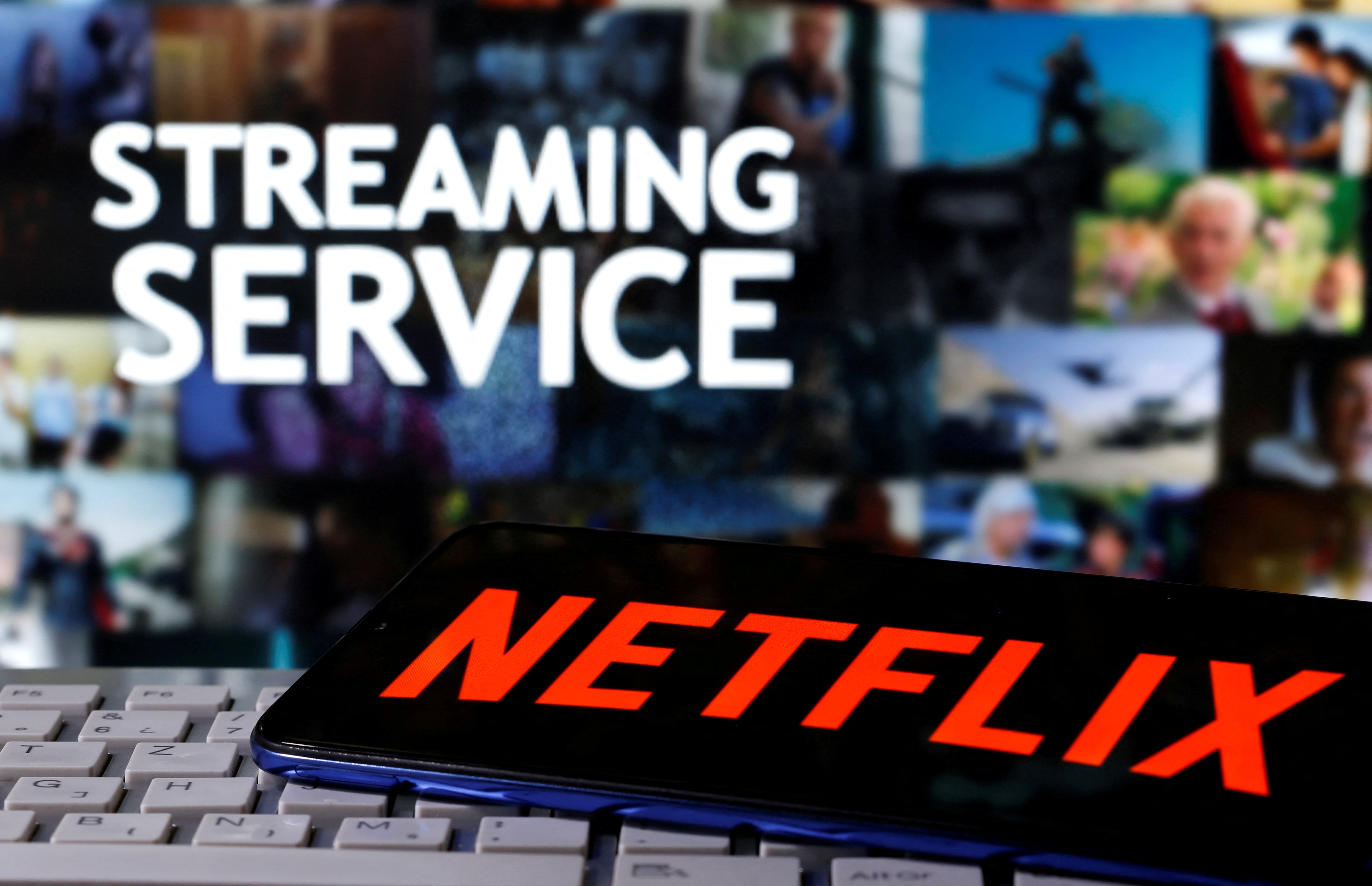 A smartphone with the Netflix logo is seen on a keyboard in front of displayed "Streaming Service" words in this illustration taken March 24, 2020. 