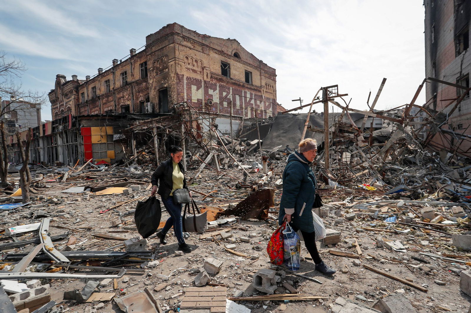 Residents carry their belongings near buildings destroyed in the course of the Russian invasion of Ukraine, in the southern port city of Mariupol, Ukraine on April 10, 2022.