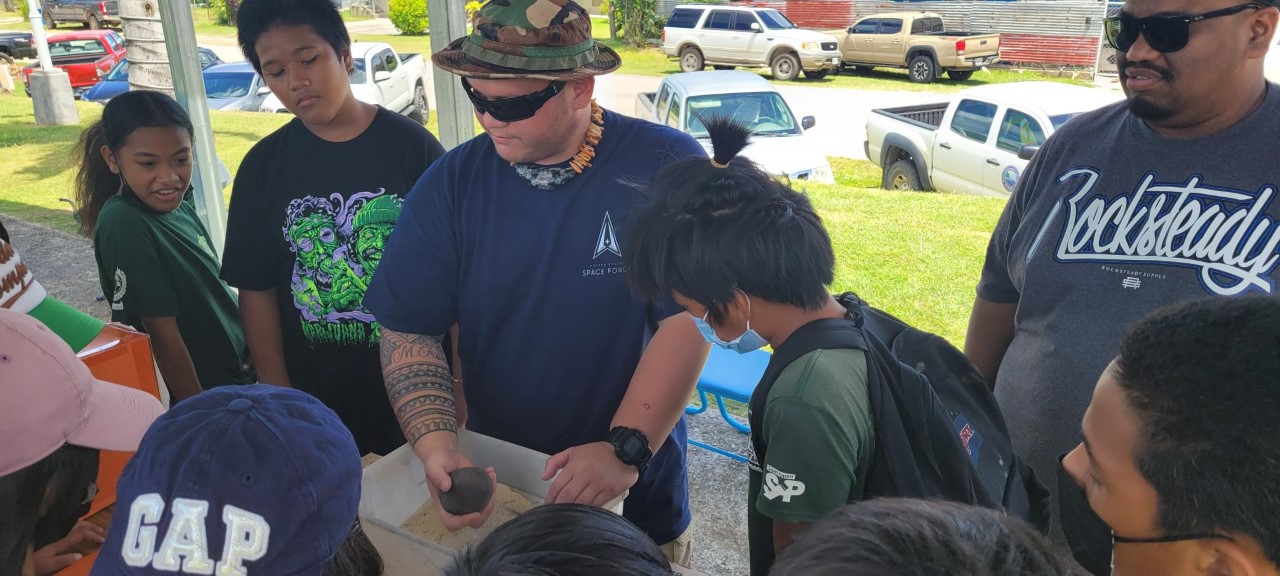 An environmental exhibitor shows students the tip of an unexploded ordnance.