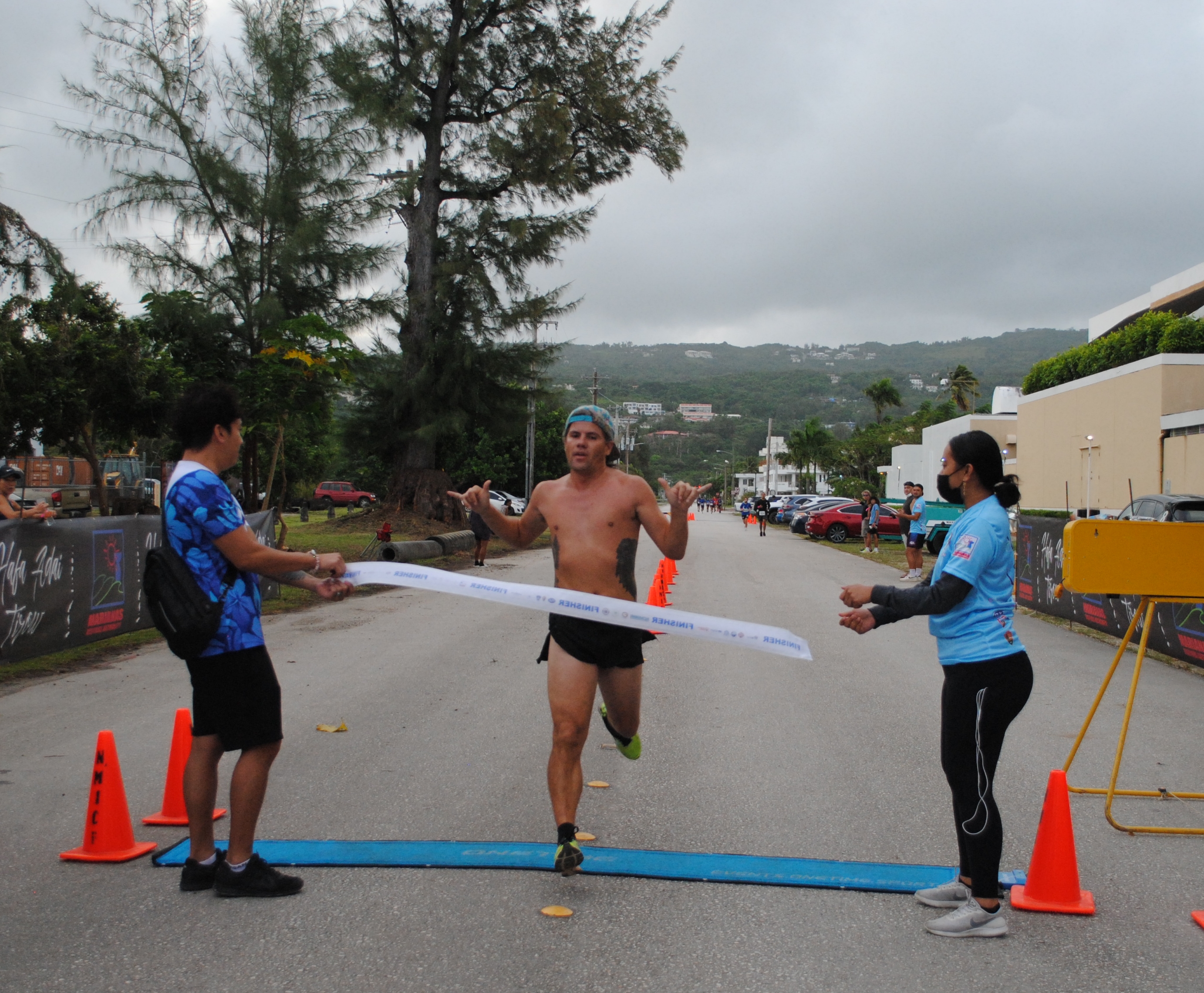 Keith Longuski gestures as he crosses the finish line of the Saipan Half Marathon/10K category on Saturday at American Memorial Park.