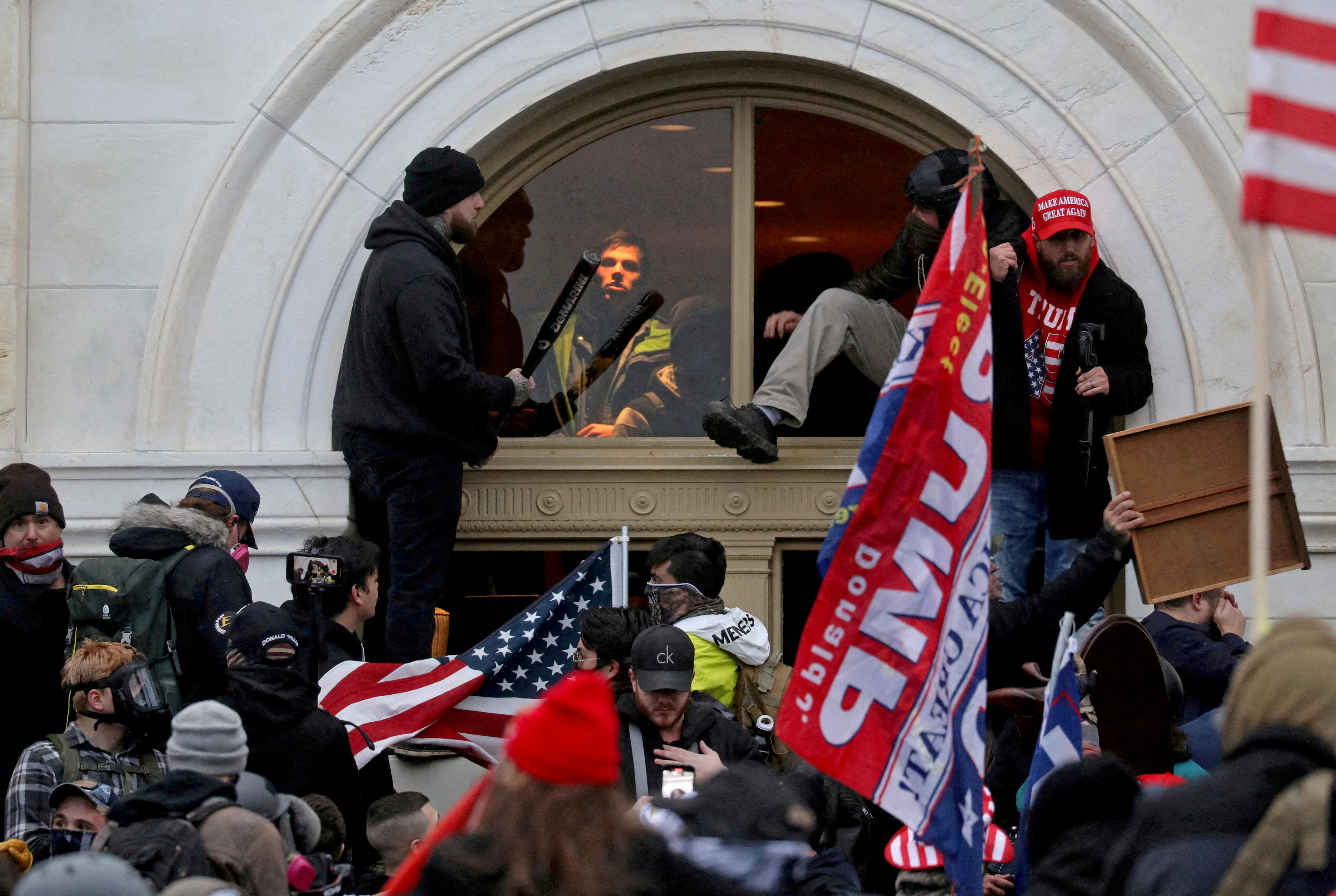 A mob of supporters of then-President Donald Trump climb through a window they broke as they storm the U.S. Capitol in Washington, D.C., Jan. 6, 2021.