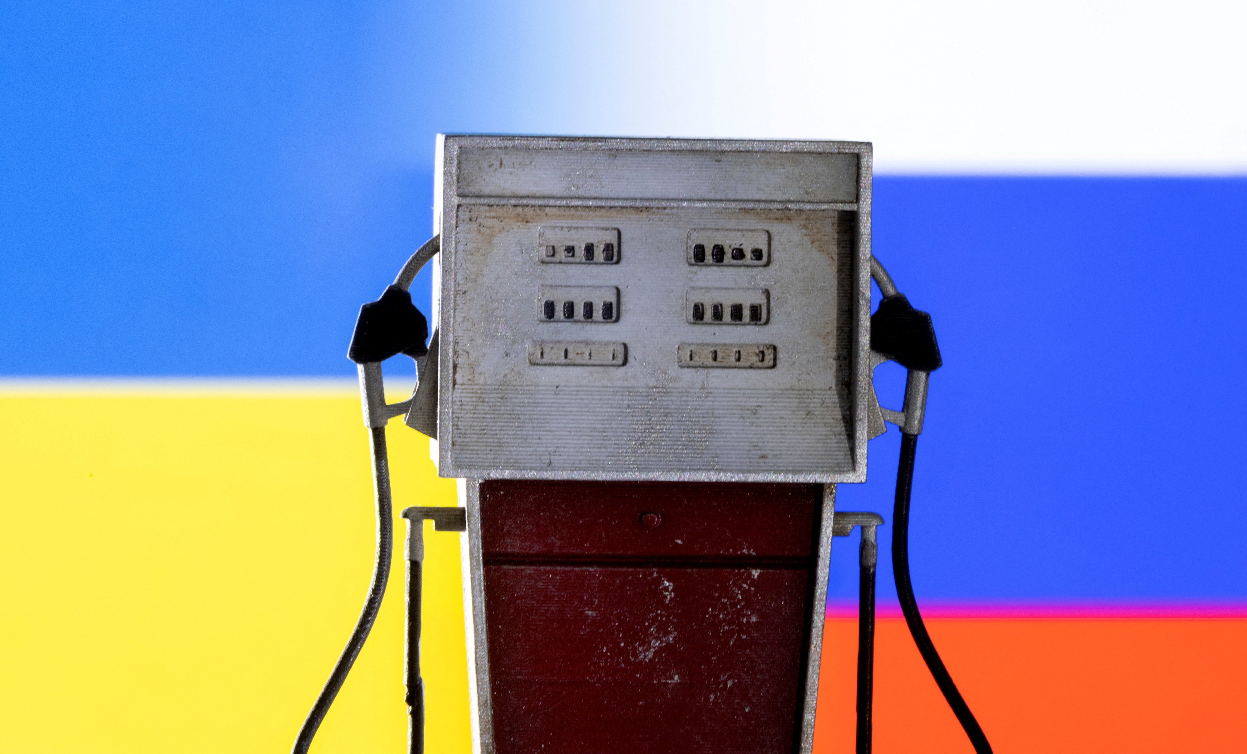 A model of a petrol pump is seen in front of Ukraine and Russian flag colors in this illustration taken March 25, 2022.