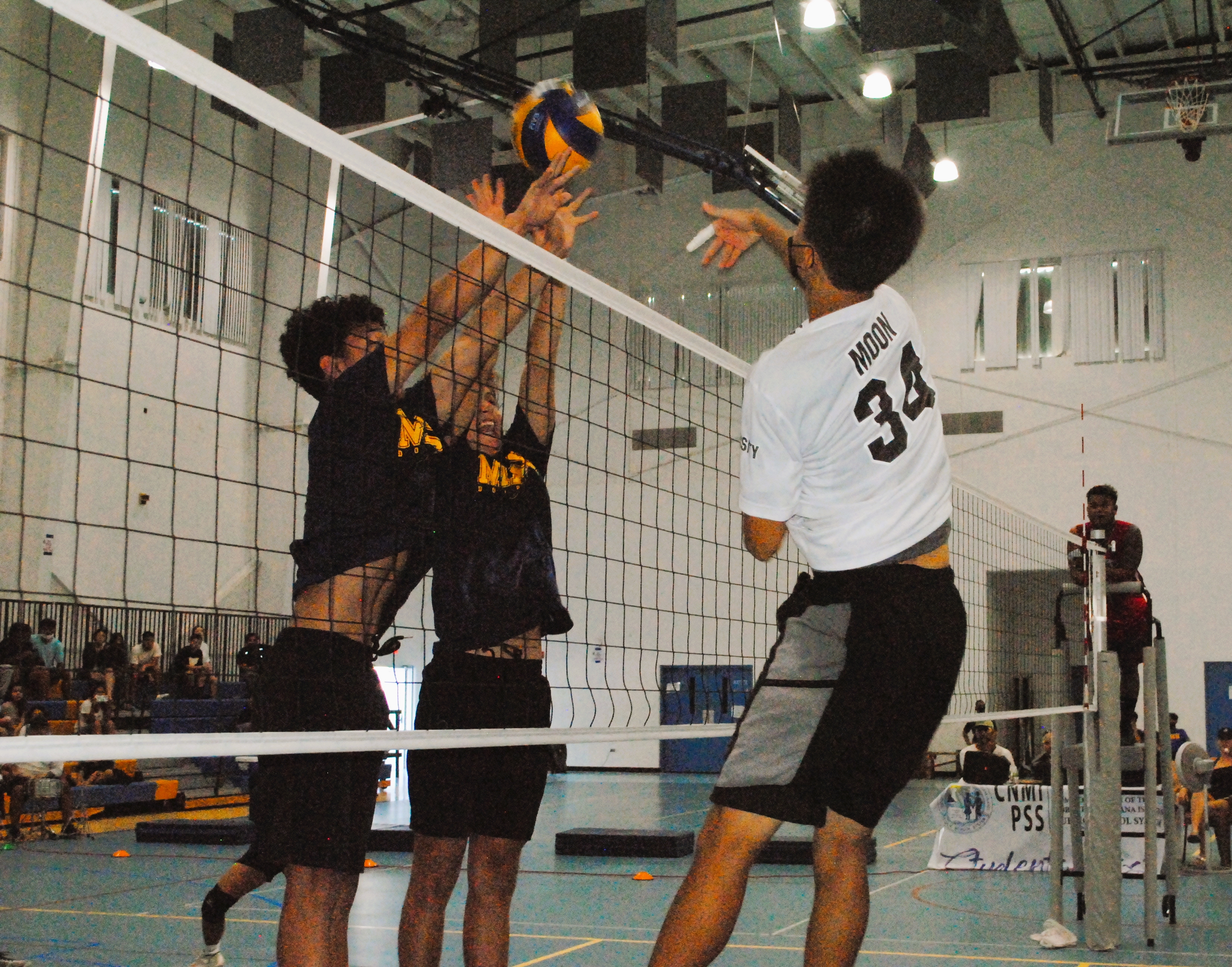 GCA's Moon connects the spike as two MHS player go up for the block during the championship game of the PSS High School Boys Volleyball League on Saturday at  MHS gym.