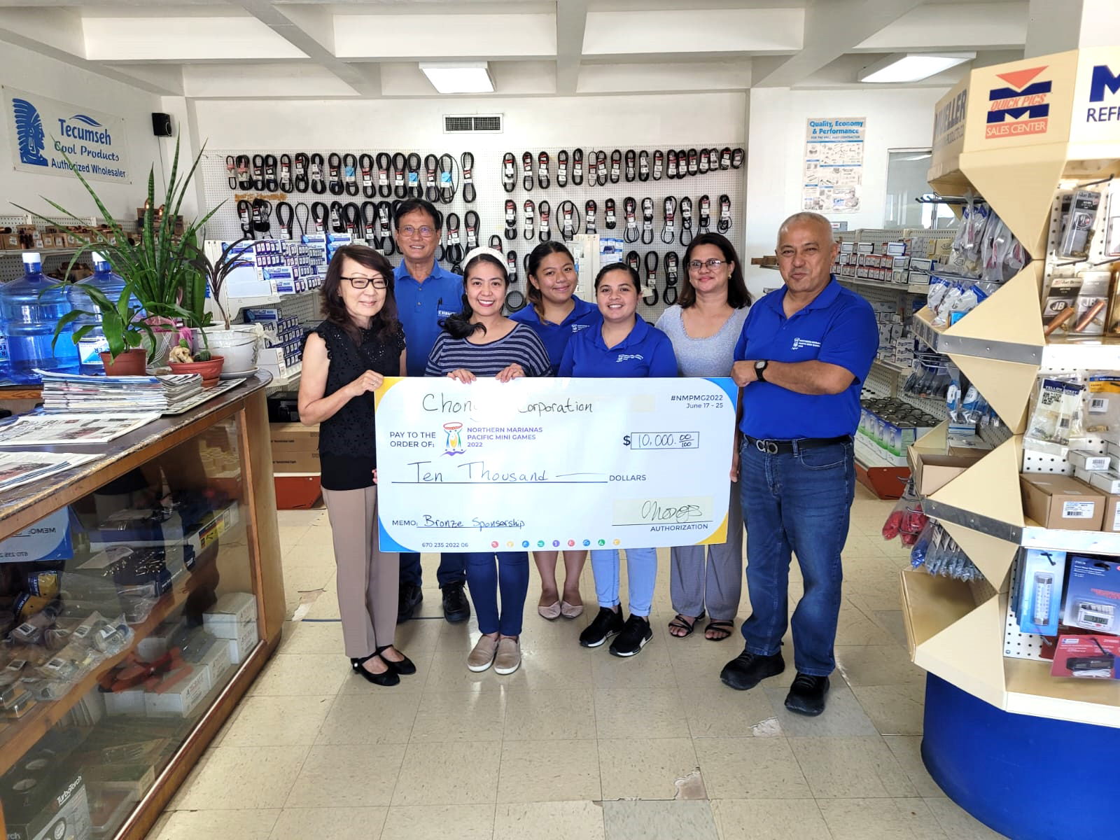 Chong's Corporation President Joanna Pai, left, and employees with Northern Marianas Pacific Mini Games 2022 CEO Ben Babauta, right, and games organizing committee members hold the check for $10,000 donated by Chong’s at its office in Gualo Rai Thursday.
