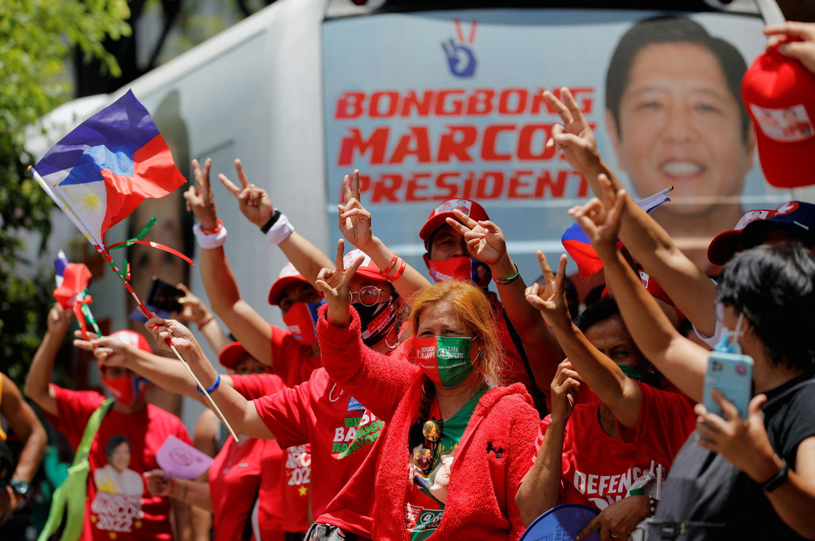 Supporters of presidential candidate Ferdinand "Bongbong" Marcos Jr. gesture and celebrate as partial results of the 2022 national elections show him with a wide lead over rivals, outside the candidate's headquarters in Mandaluyong City, Metro Manila, May 10, 2022.