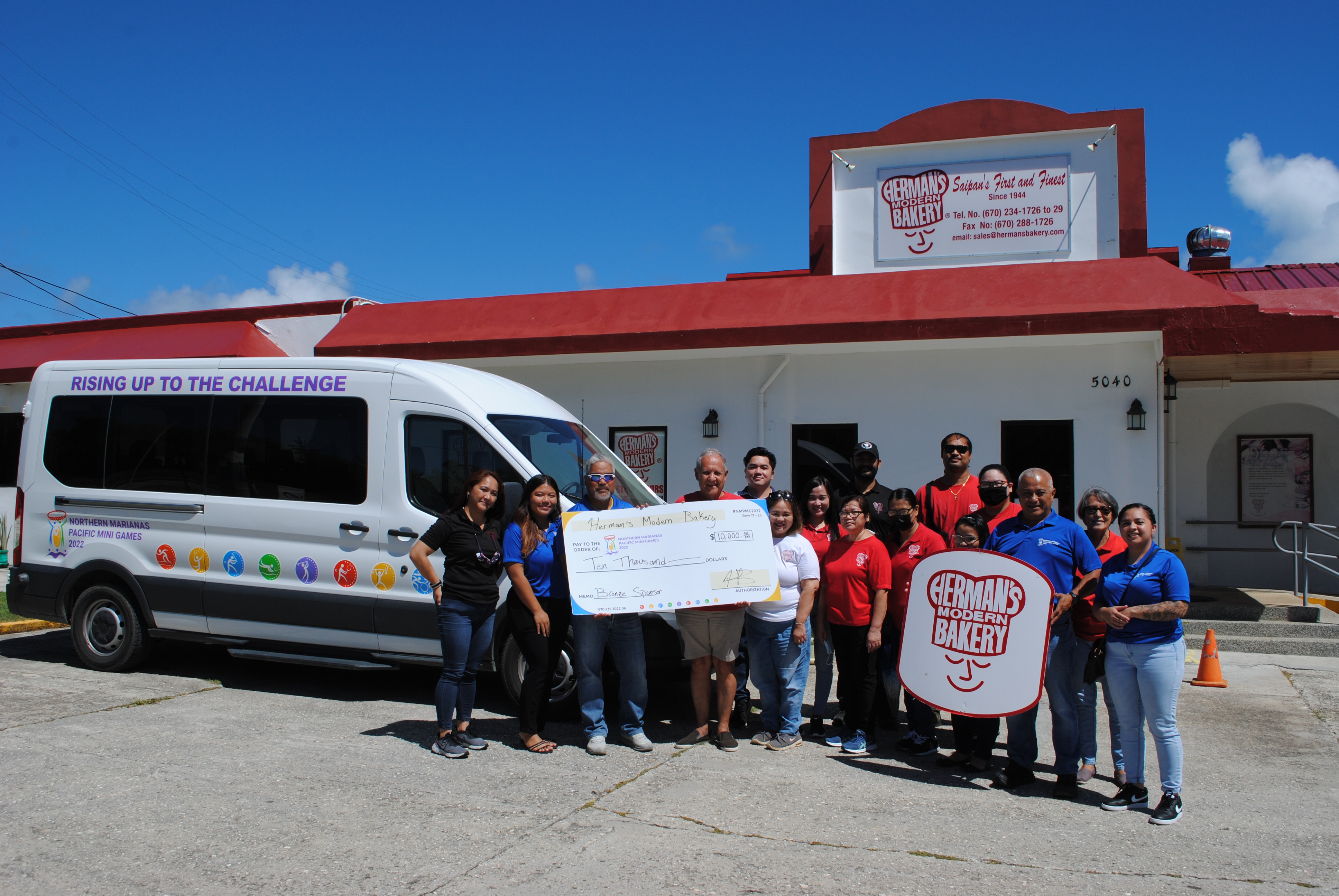 2022 Pacific Mini Games Organizing Committee Chairman Marco Peter and Herman's Modern Bakery President Herman T. Guerrero hold the ceremonial check for $10,000 donated by Herman’s to the organizing committee on Monday. Also in photo  are the organizing committee’s CEO Ben Babauta, committee members and Herman's Modern Bakery staff.
