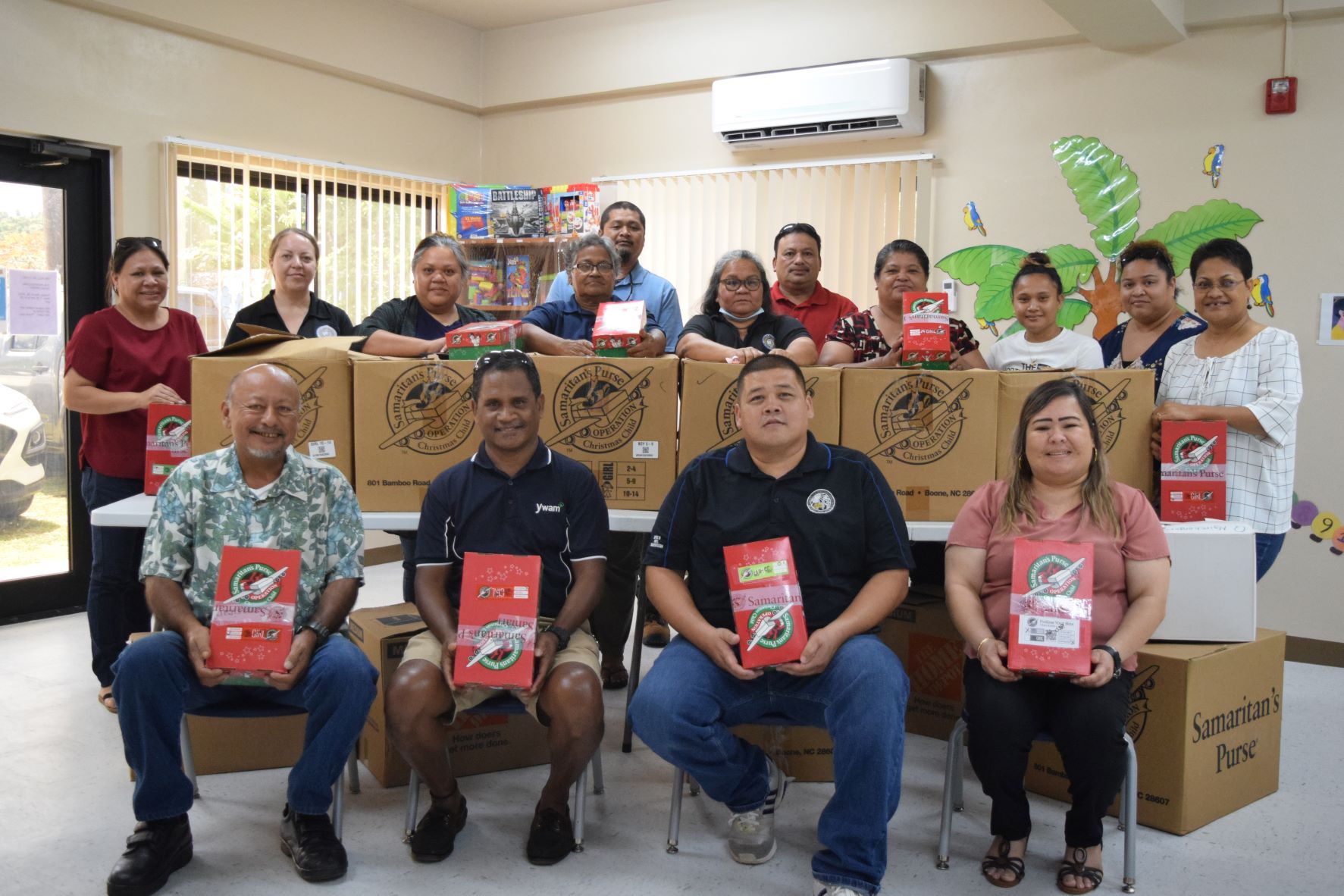 From left, seated: Department of Community and Cultural Affairs Secretary Joseph P. Deleon Guerrero, Youth with a Mission Saipan Director Rengesuul Yobech, Public School System Pupil Transportation Director Shawn San Nicolas and Division of Youth Services Administrator Vivian Sablan hold some of the donations at the Tanapag Youth Center. Behind them are DYS staff members.