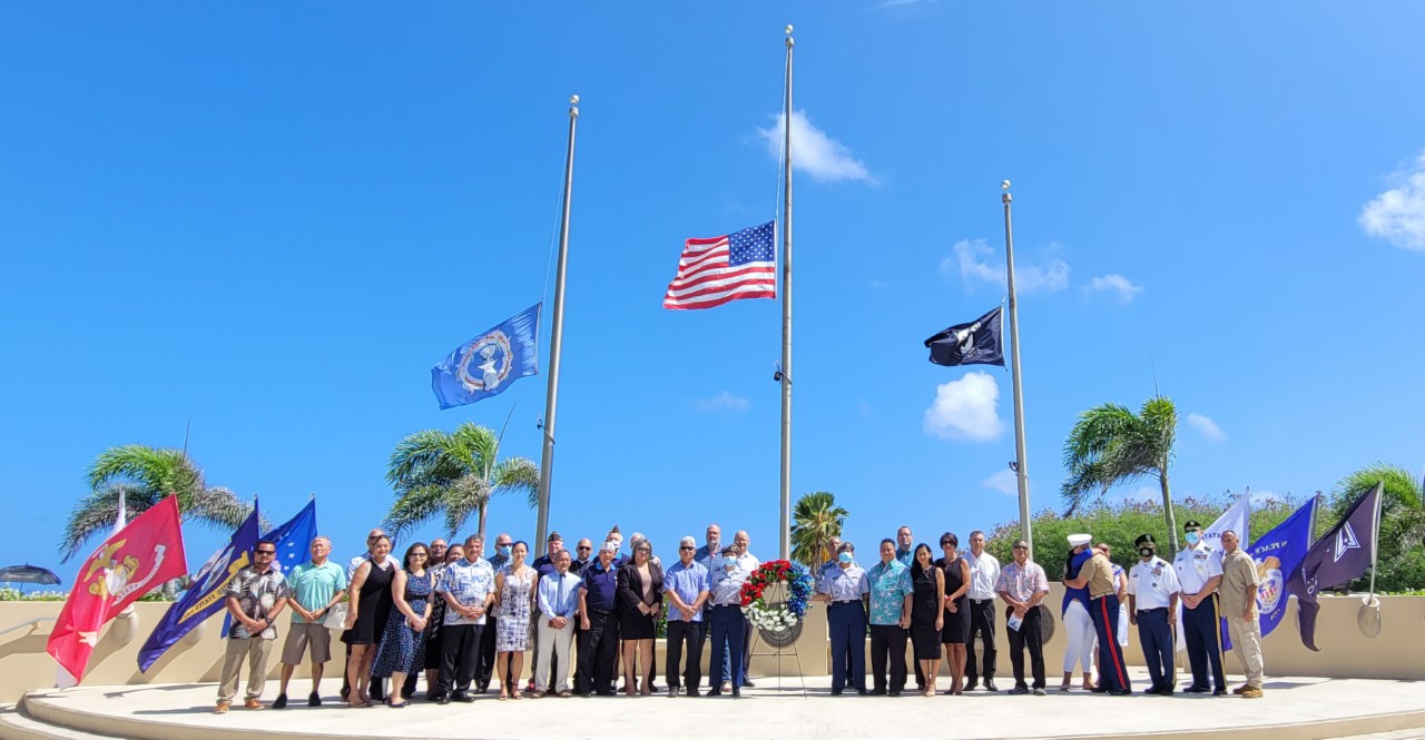 Dignitaries, veterans, and servicemembers pose for a photo with the ceremonial wreath.