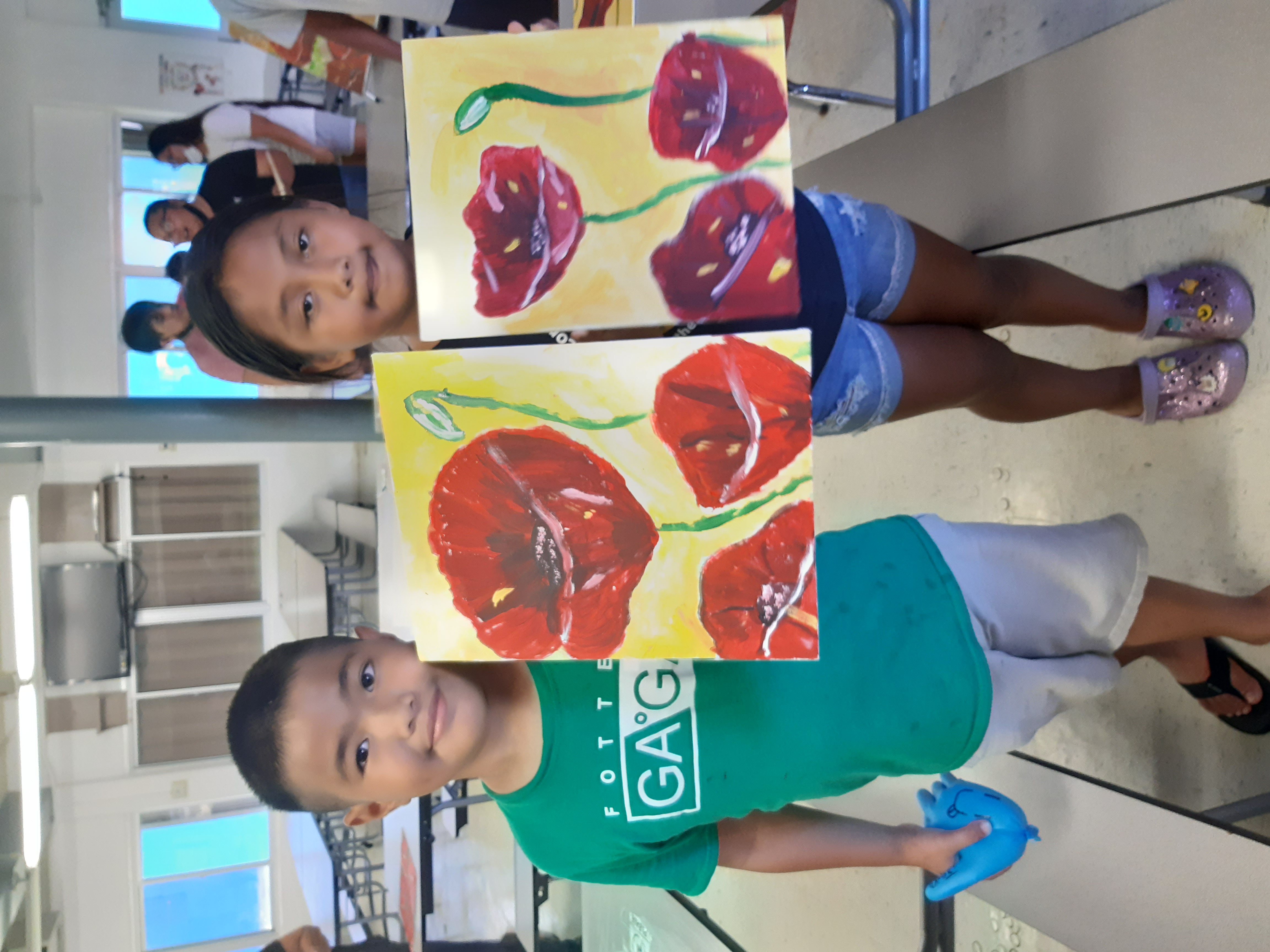 Geovan  Hocog,  left,  and  Ge'selle  Barcinas  display  their  artwork  created  during  a painting workshop organized on May 21, 2022, by the Marianas Visitors Authority at Rita H. Inos Jr./Sr. High School on Rota in the Marianas.  The event was held in celebration of Marianas Tourism Month.