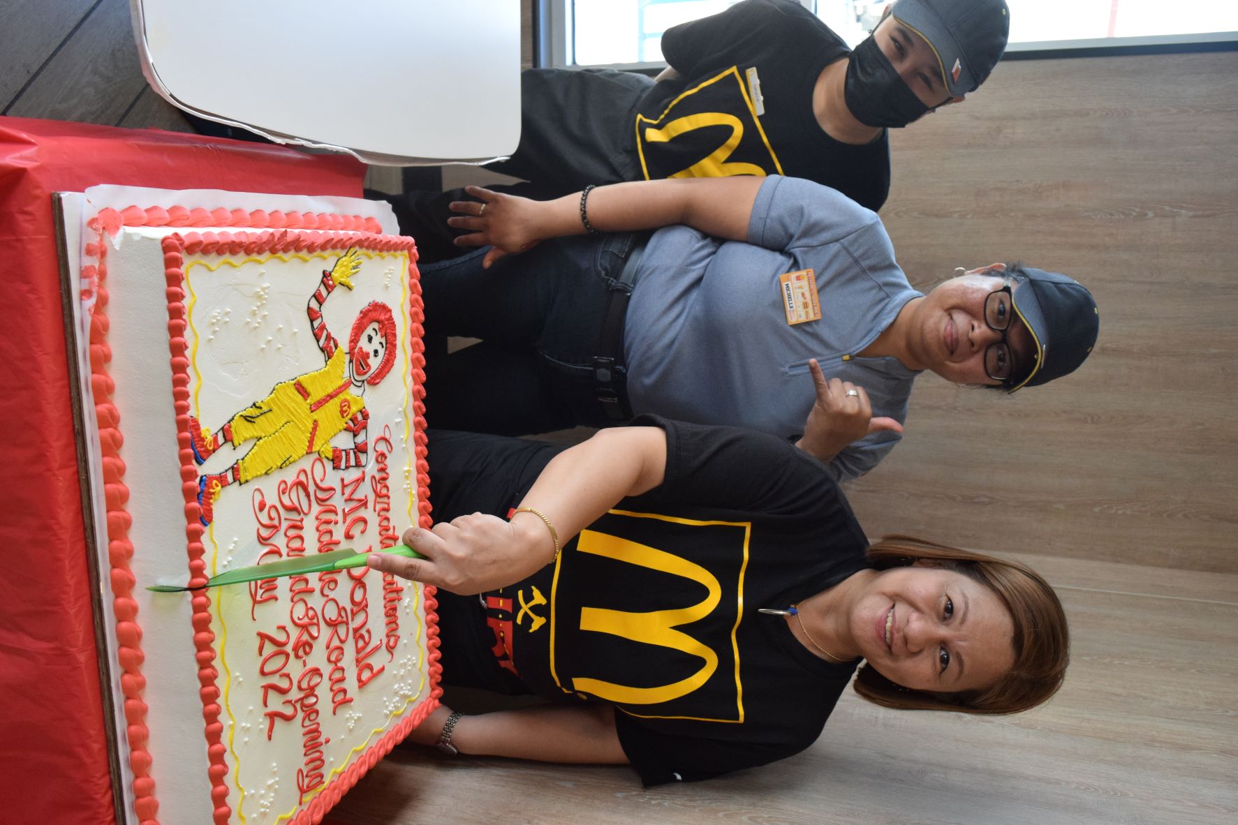 McDonald's Middle Road general manager Joyce Asistores cuts the cake as she poses for a photo with service crewmembers Gracelyn Babauta and Michelle Tudela.