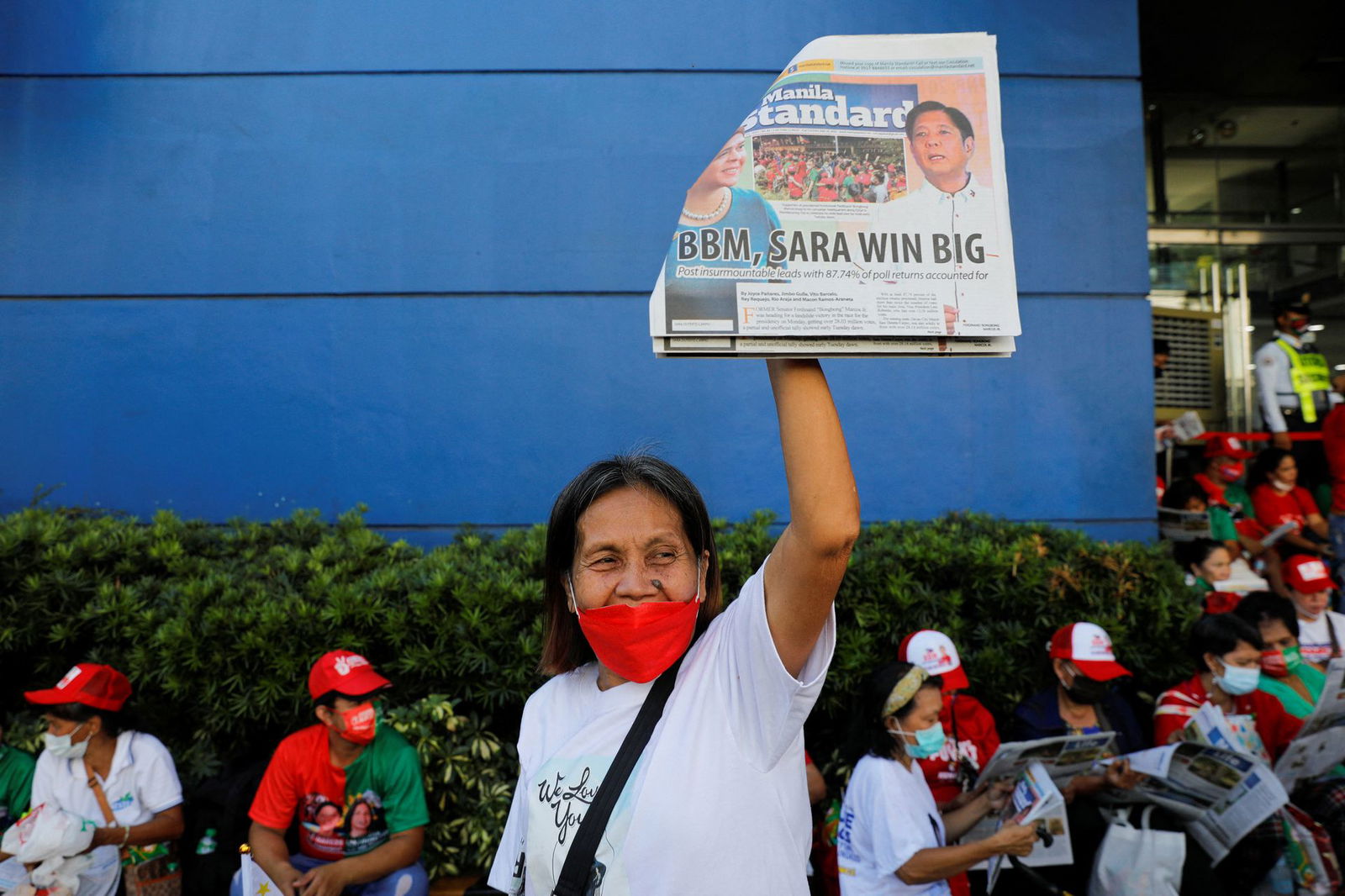 A supporter of presidential candidate Ferdinand "Bongbong" Marcos Jr. holds up a newspaper with his landslide victory on the headline as people gather to celebrate at his campaign headquarters in Mandaluyong City, Metro Manila on May 10, 2022.