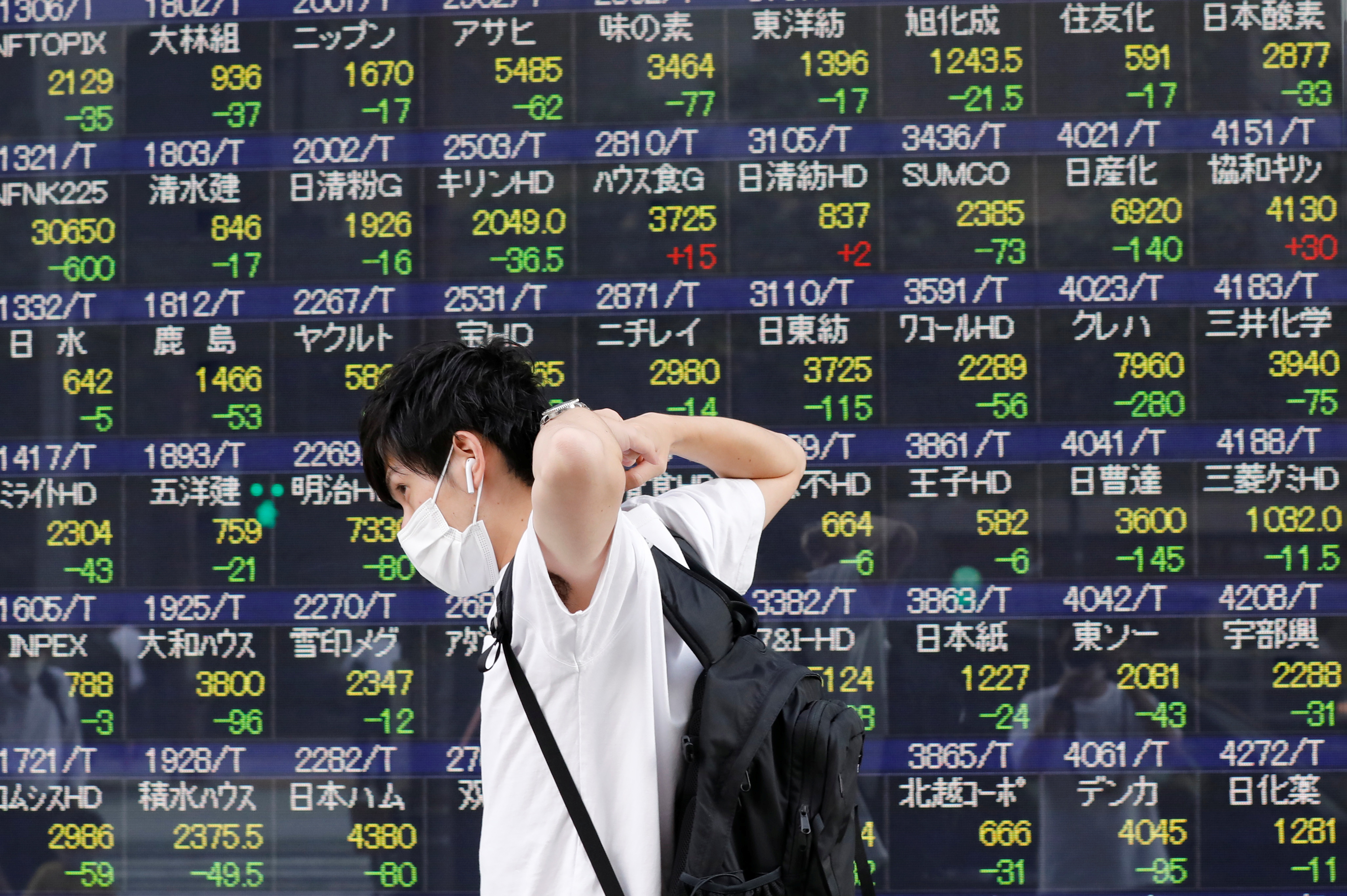 A man wearing a protective mask, amid the Covid-19 outbreak, walks past an electronic board displaying Japan's Nikkei index outside a brokerage in Tokyo, Japan, Sept. 21, 2021.