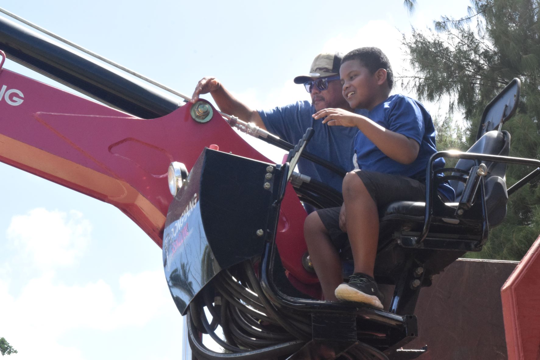 Graydon Ngiralmau, 10, is assisted by Department of Public Works Knuckle Boom Truck Operator Bryan Blas.