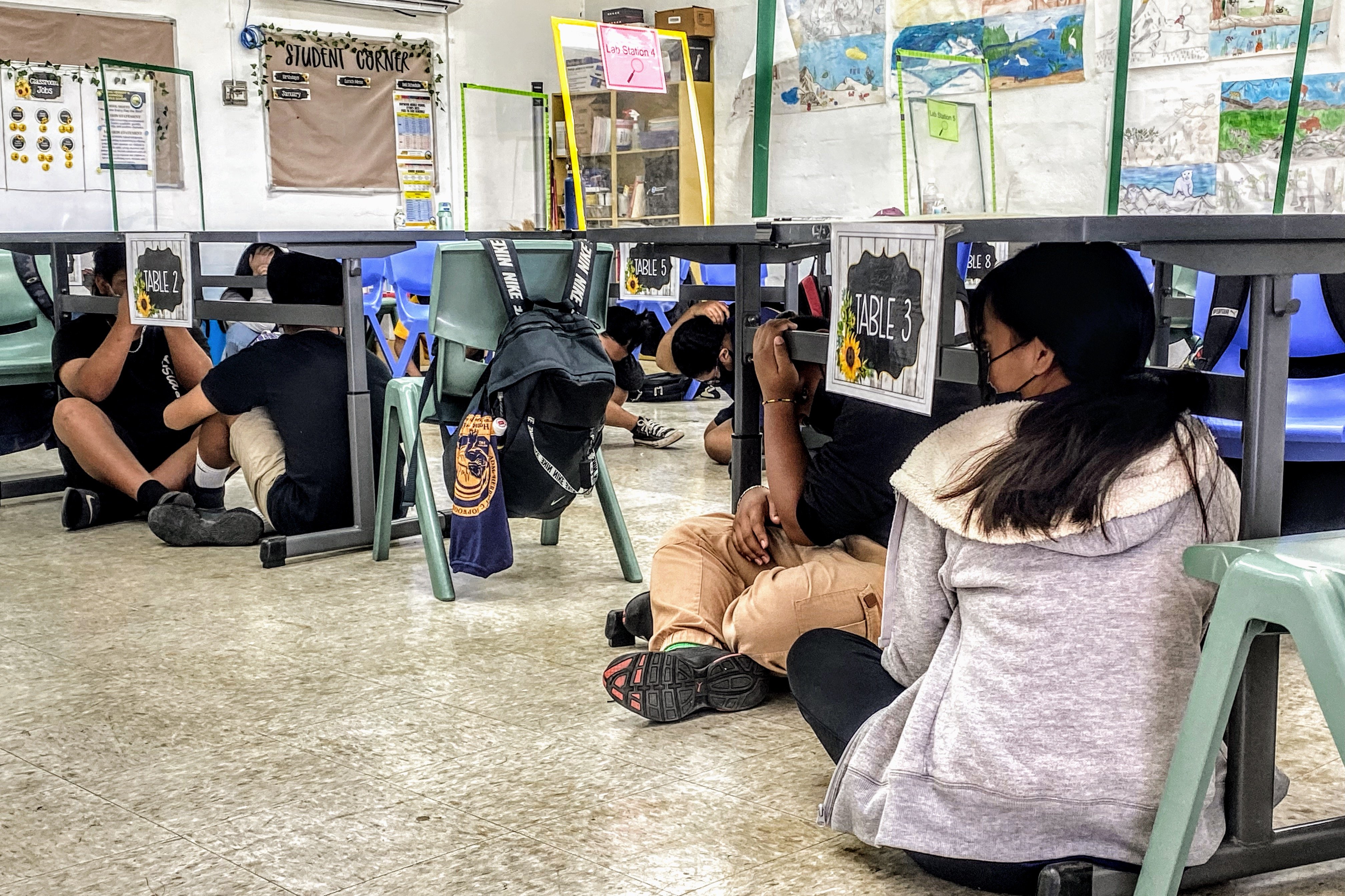 Hopwood Middle School students hide under their desks during a mock magnitude-8 earthquake before  evacuating to the Parks & Recreation compound in As Perdido as part of Tuesday’s tsunami drill. 