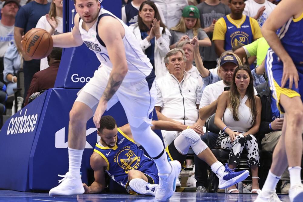 Golden State Warriors' Stephen Curry lies on the court as Dallas Mavericks' Luka Doncic dribbles during the third quarter in Game 4 of NBA basketball playoffs Western Conference finals in Dallas on Tuesday, May 24, 2022.