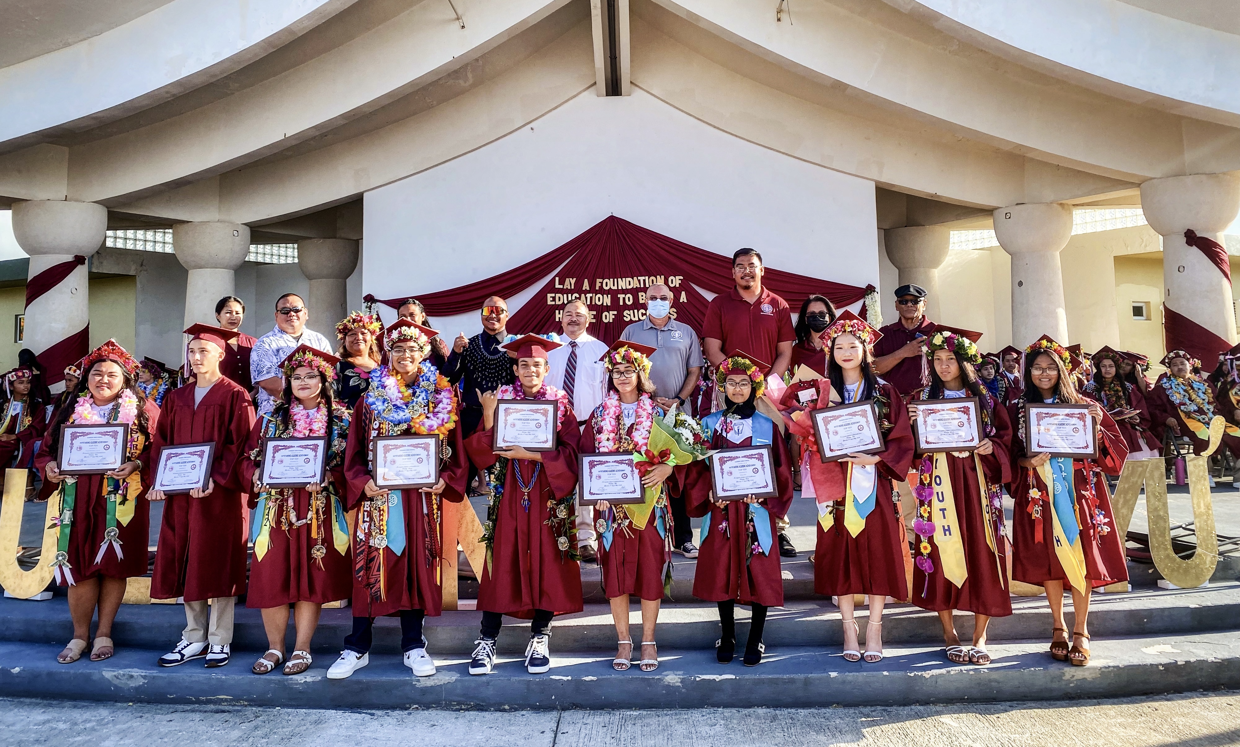 The top ten graduates of Kagman High School are Shannea Mae Javate Dino, valedictorian; Dasol Erin Kim salutatorian; Helen Chen, third; Rabeya Akter, fourth; Kayla Patriz Tanate San Nicolas, fifth; Ezra Gabriel Camacho Towai, sixth; Ely Joseph De Guzman Taitano, seventh; Mikyla Cruz Capalad, eight; Alex Benjamin Menchikh Megino, ninth; and Princess Rikki Dela Cruz Lacson, tenth. Also in photo are Board of Education Chairman Gregory Pat Borja, Vice Chairman Antonio L. Borja, Secretary/Treasurer Maisie B. Tenorio, Board Member Herman Atalig,  Commissioner of Education Dr. Alfred B. Ada, KHS Principal Ben Jones, Vice Principals Shirley Norita and Francisca C. Bondoc.